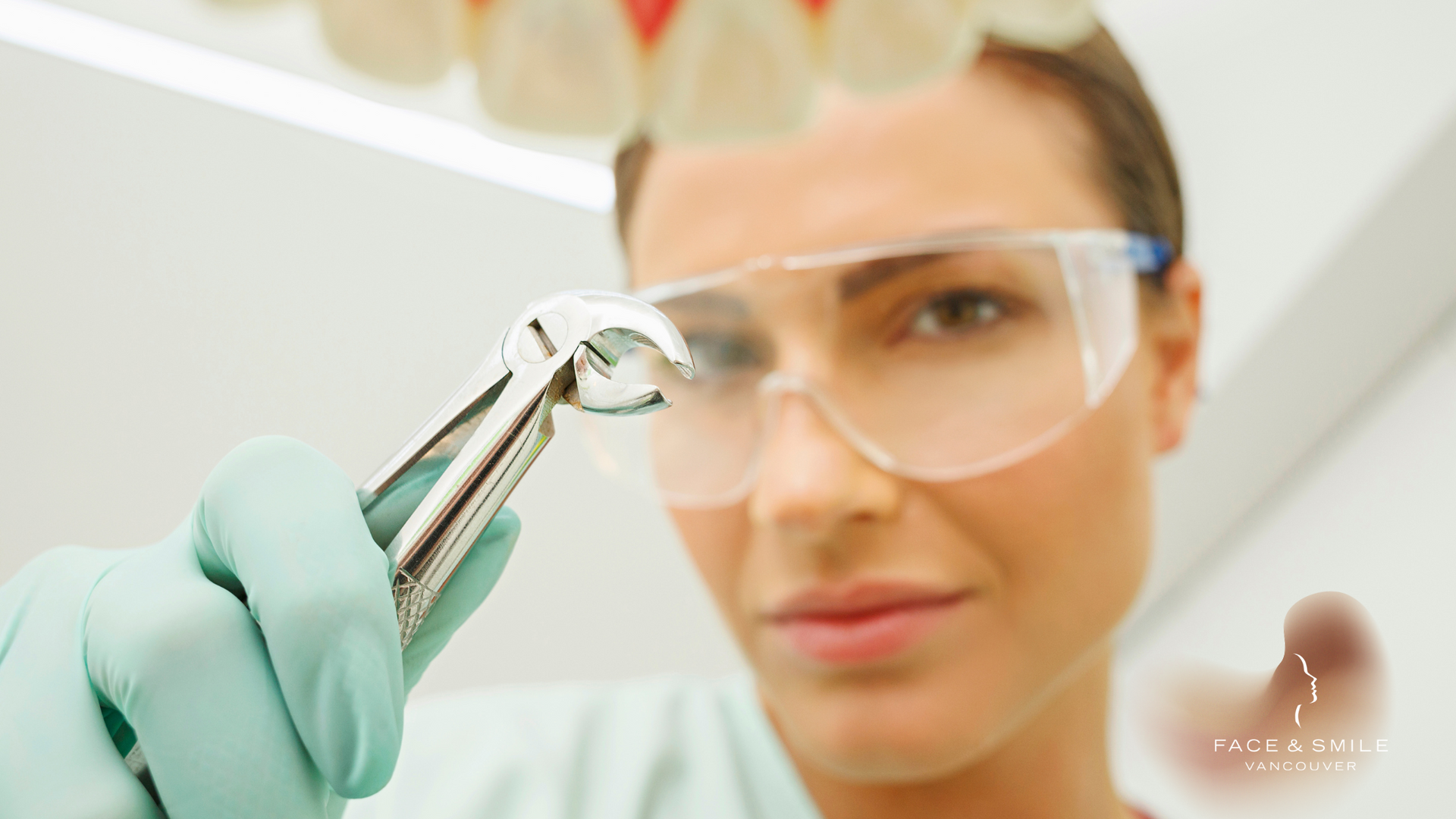 A female dentist is holding a pair of pliers in her hand.