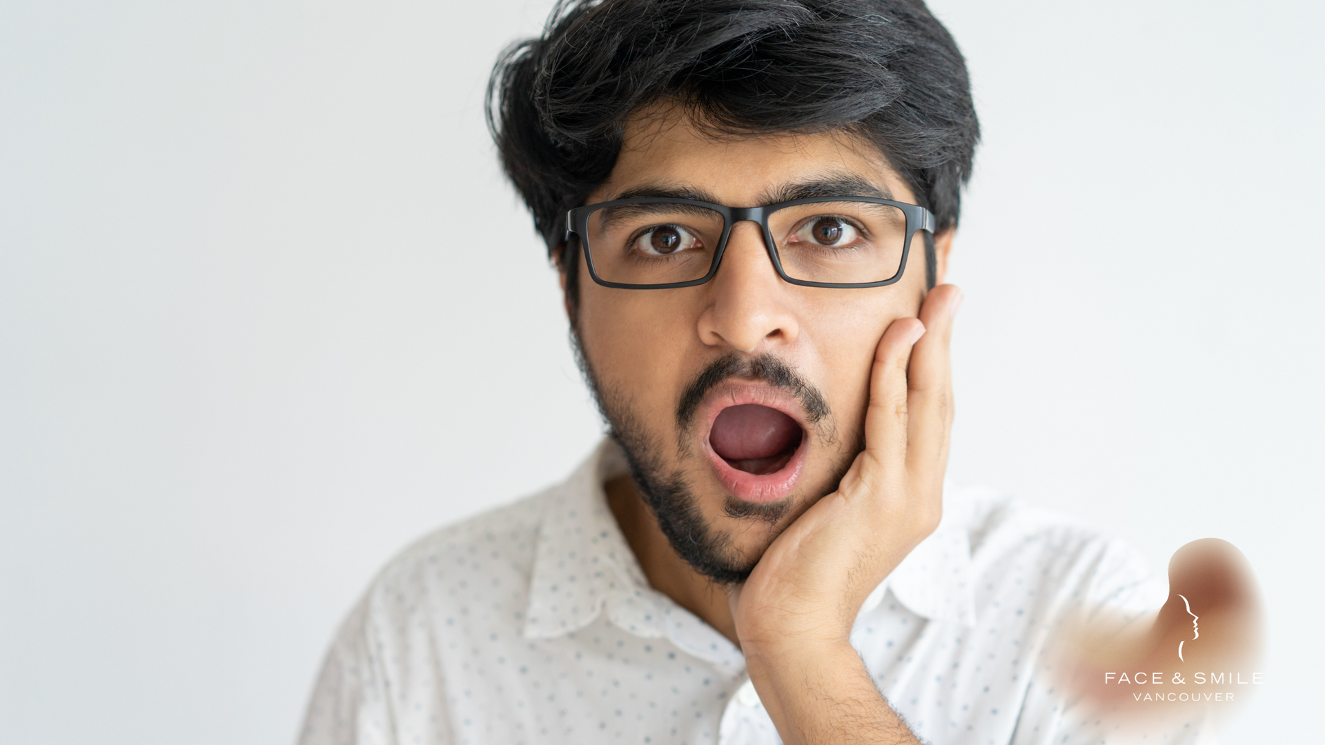 A man with glasses and a beard is making a surprised face.