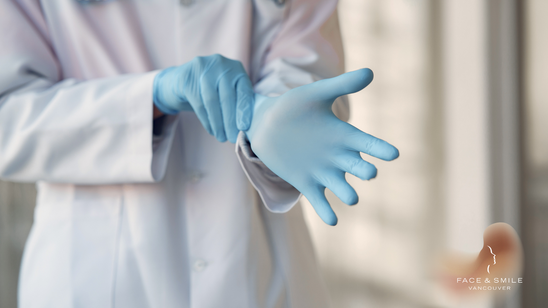 Gloved hands putting on blue medical gloves in a lab coat, close-up in a clinical setting