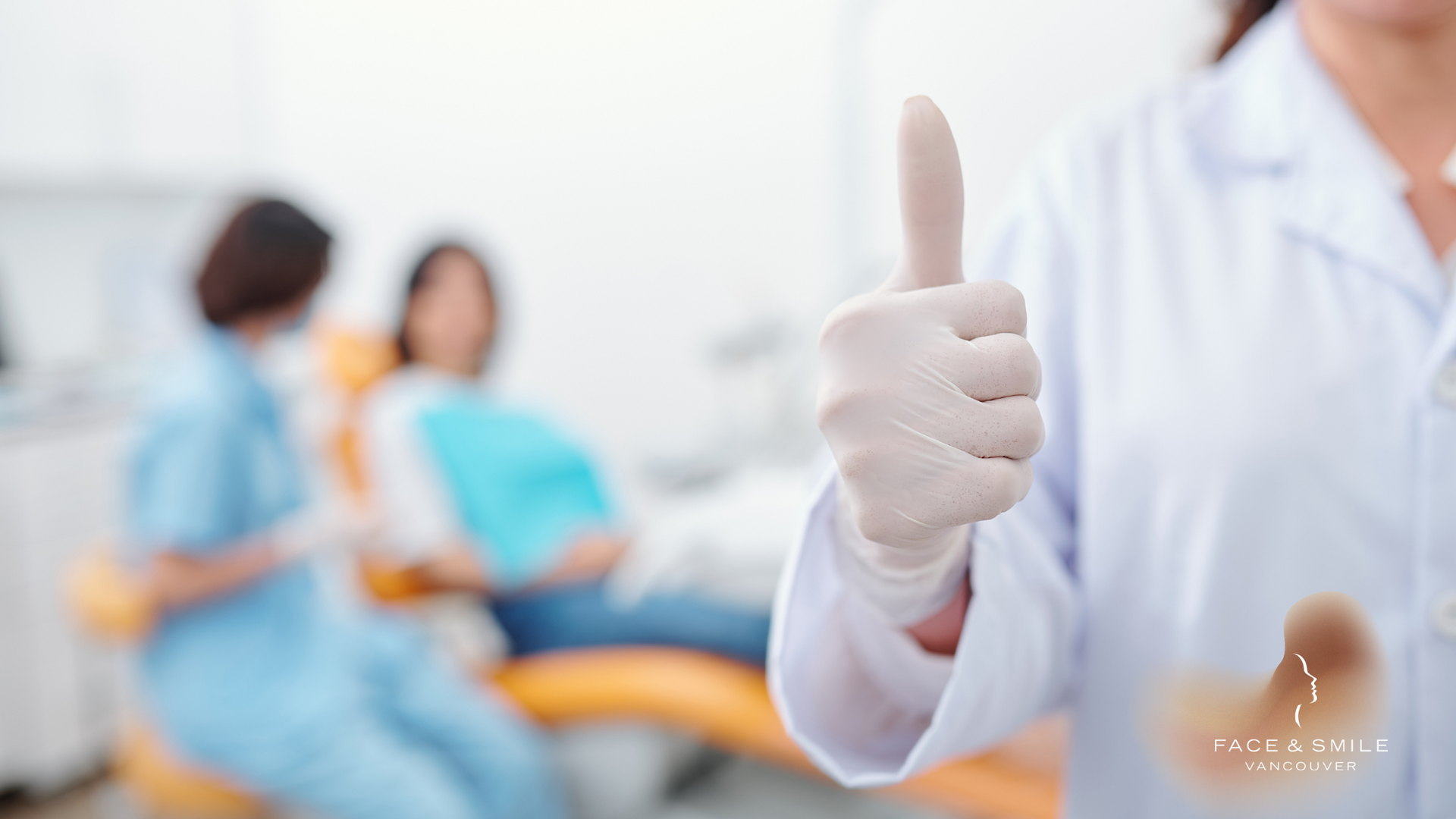 A dentist is giving a thumbs up in front of a patient in a dental chair.