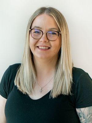 A woman wearing glasses and a black shirt is smiling for the camera.