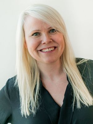 A woman with long blonde hair is smiling and wearing a black shirt.