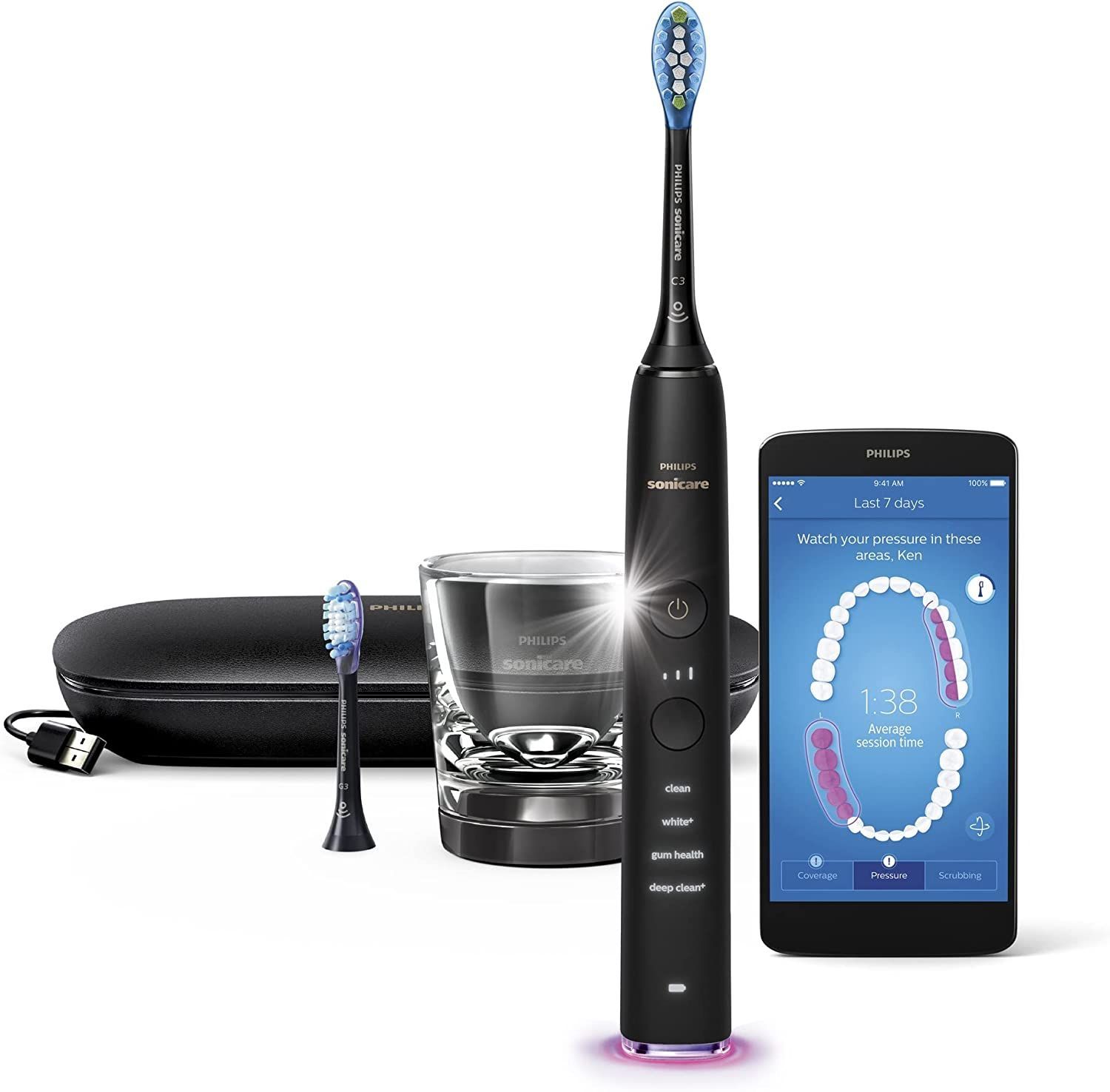 A black electric toothbrush is sitting next to a smart phone.