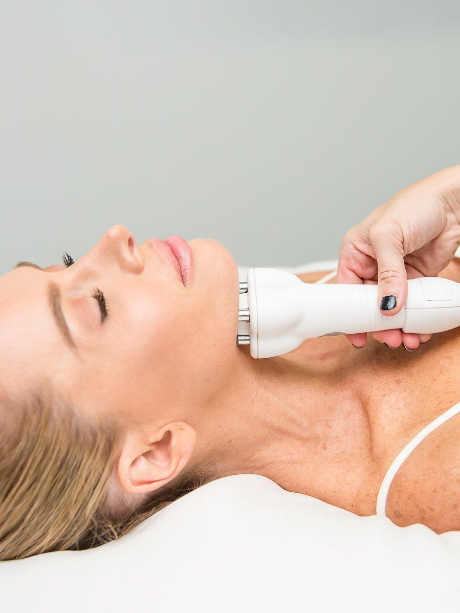 A woman is getting a facial treatment with a machine on her neck.