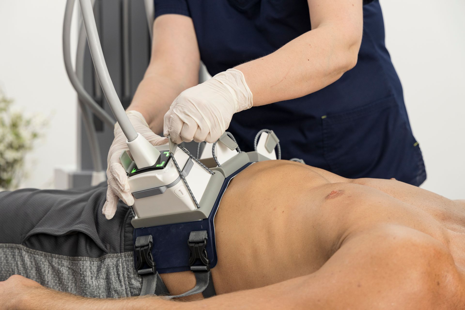A man is laying on a bed receiving a non-surgical body contouring treatment on his stomach