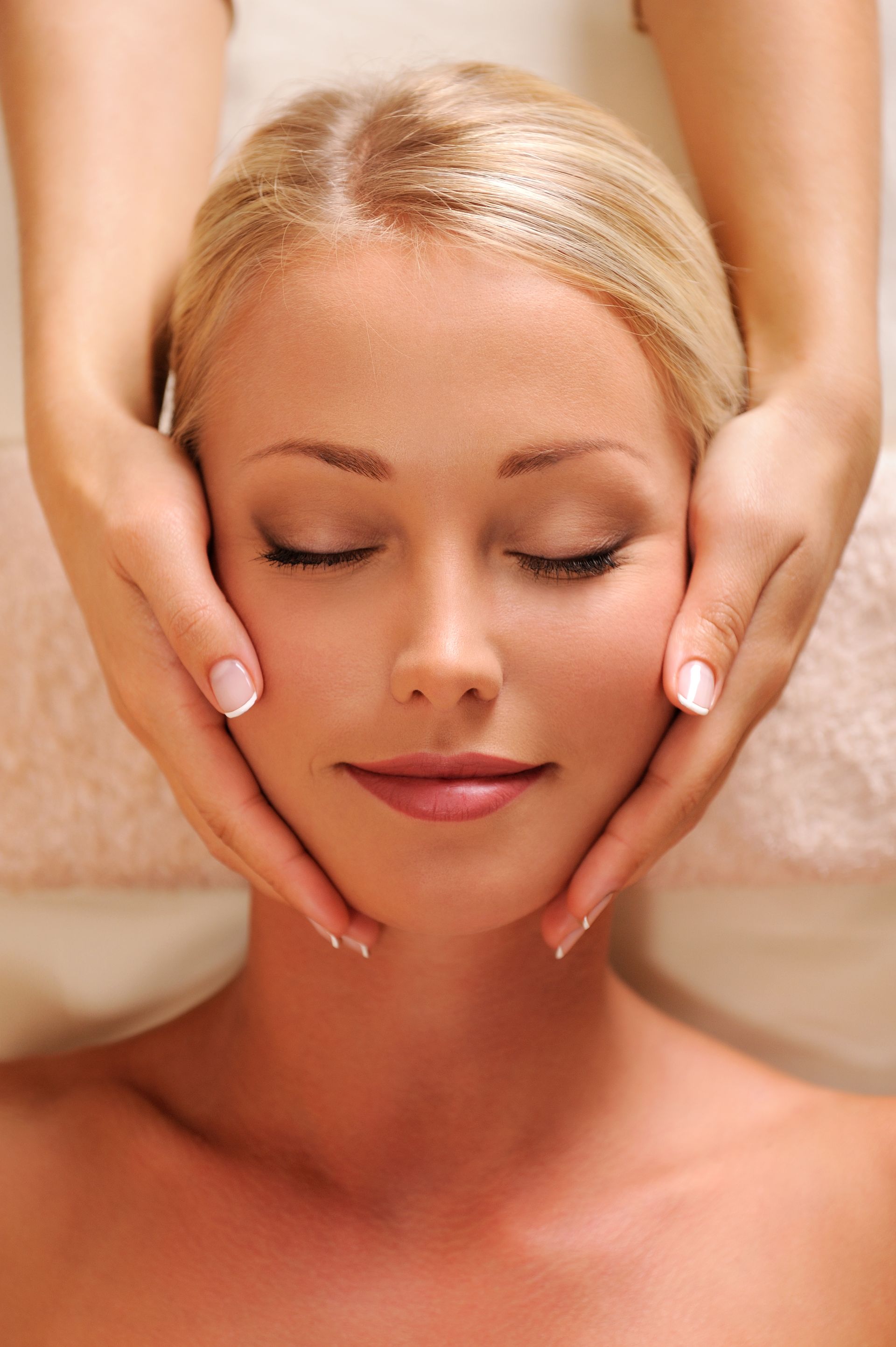 a woman is getting a facial massage with her eyes closed