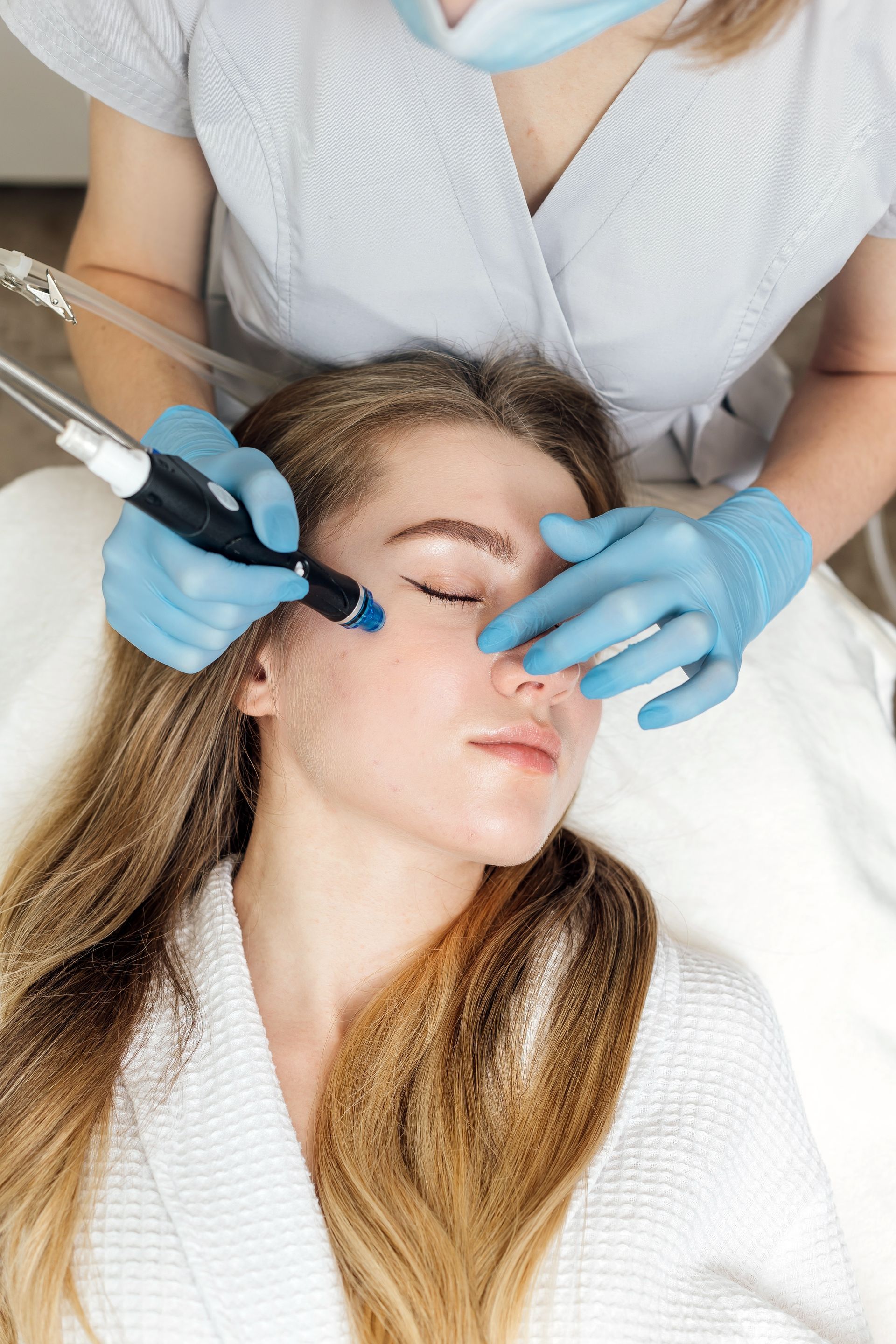 a woman with her eyes closed is getting a treatment on her face
