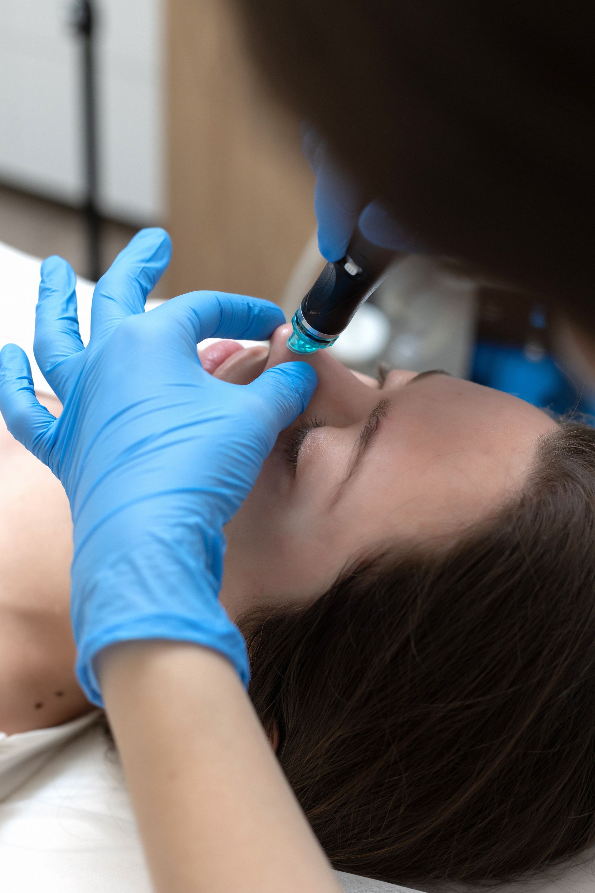 a person wearing blue gloves is examining a woman 's face