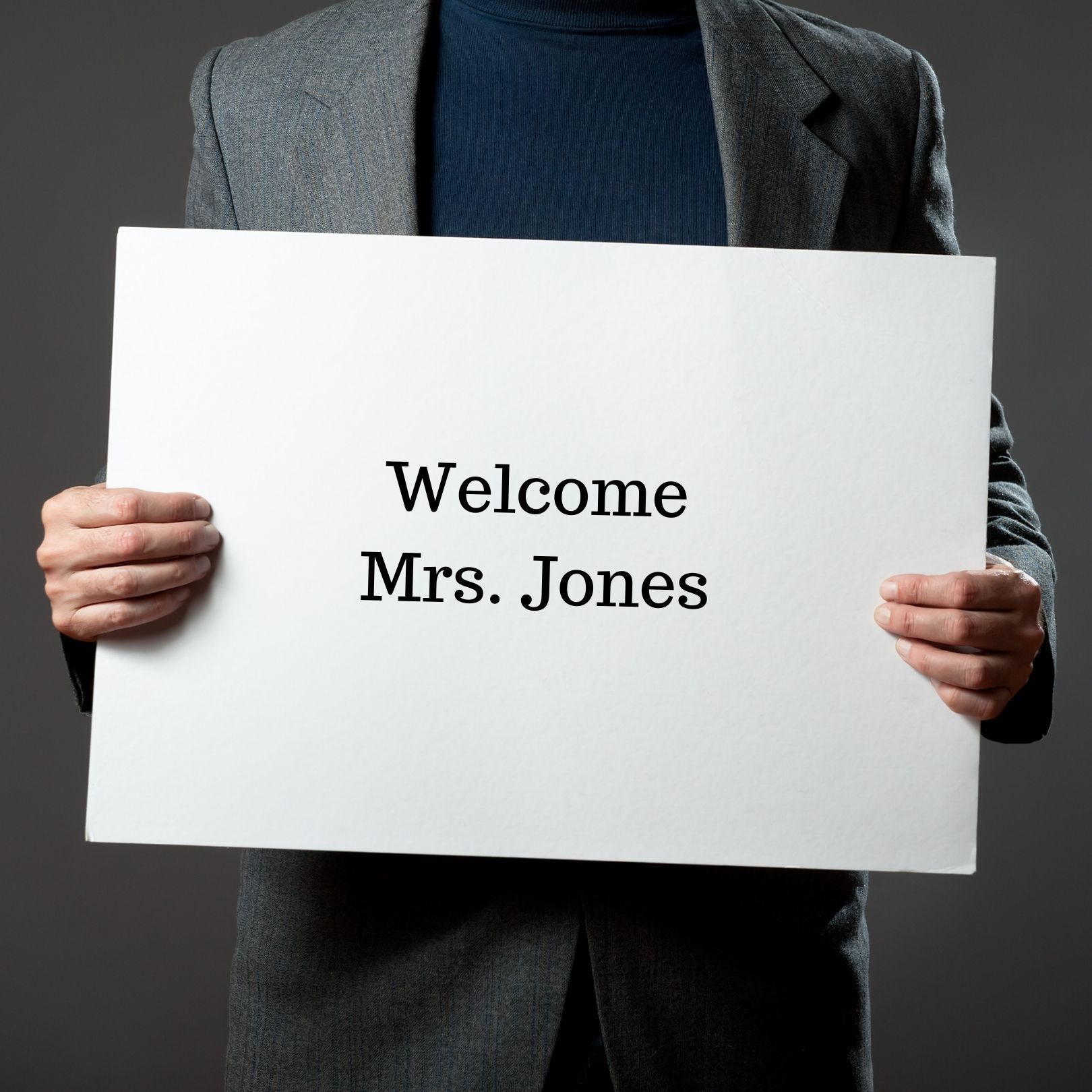 A person in a gray blazer holds a white sign that says