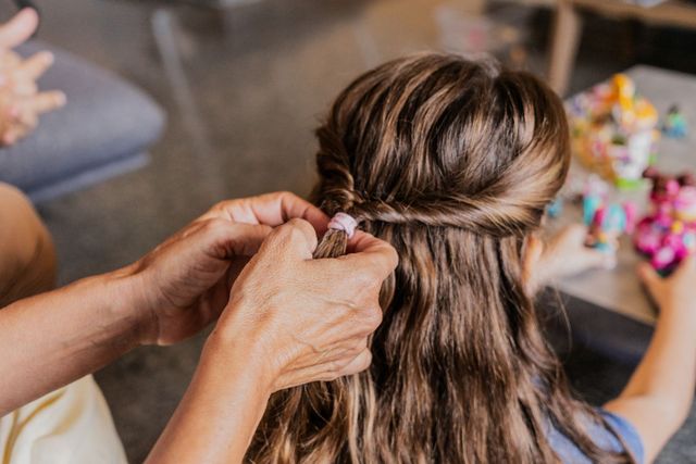 Una mujer está poniendo una pinza en el cabello de una niña.