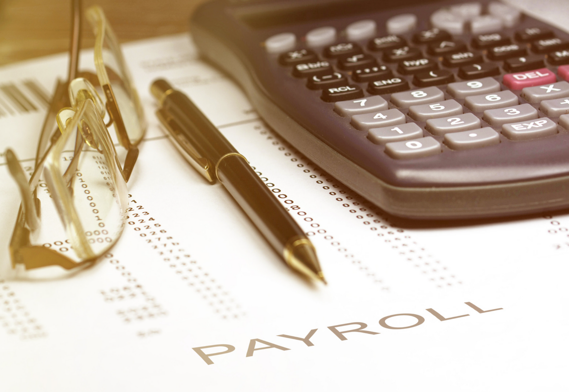 A pen glasses and a calculator on top of a payroll form