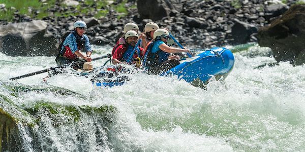 Group of People Are Rafting Down a River in Blue Raft