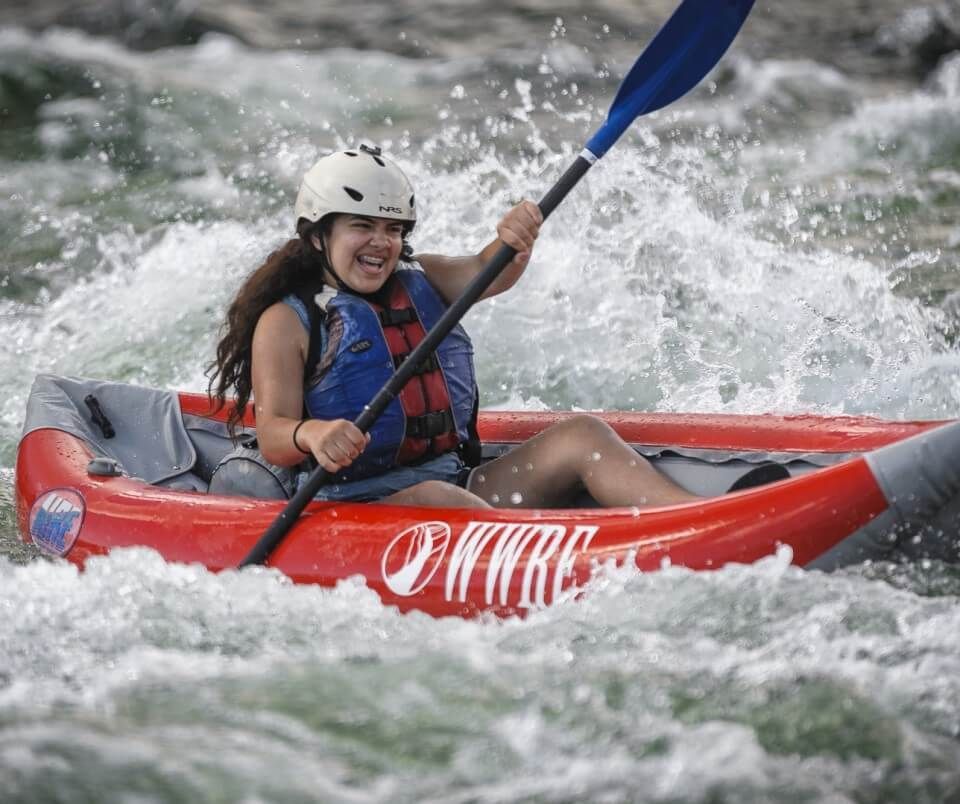 A Woman Paddling a Red Kayak in A River
