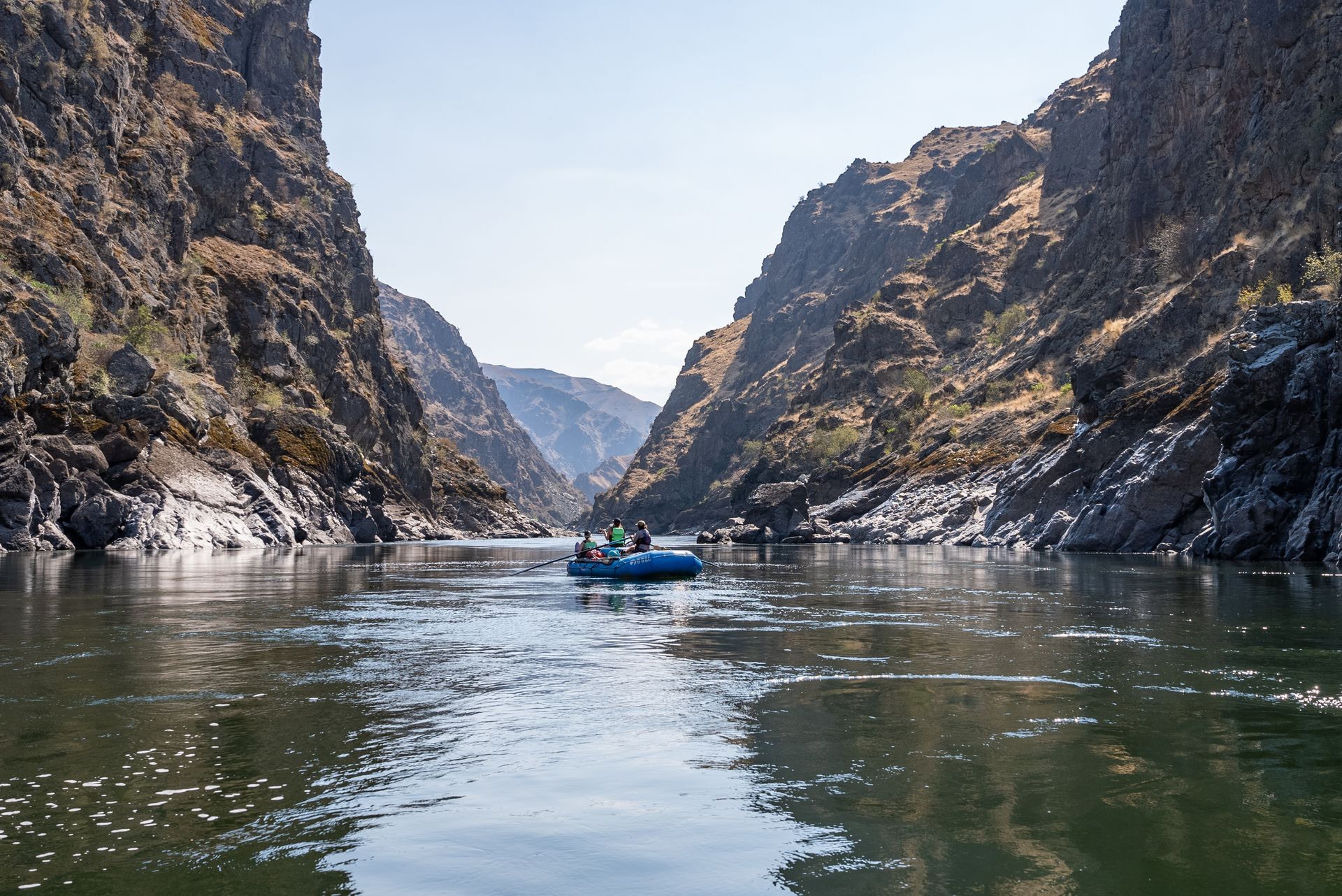 A group of people are rafting down a river in a canyon.