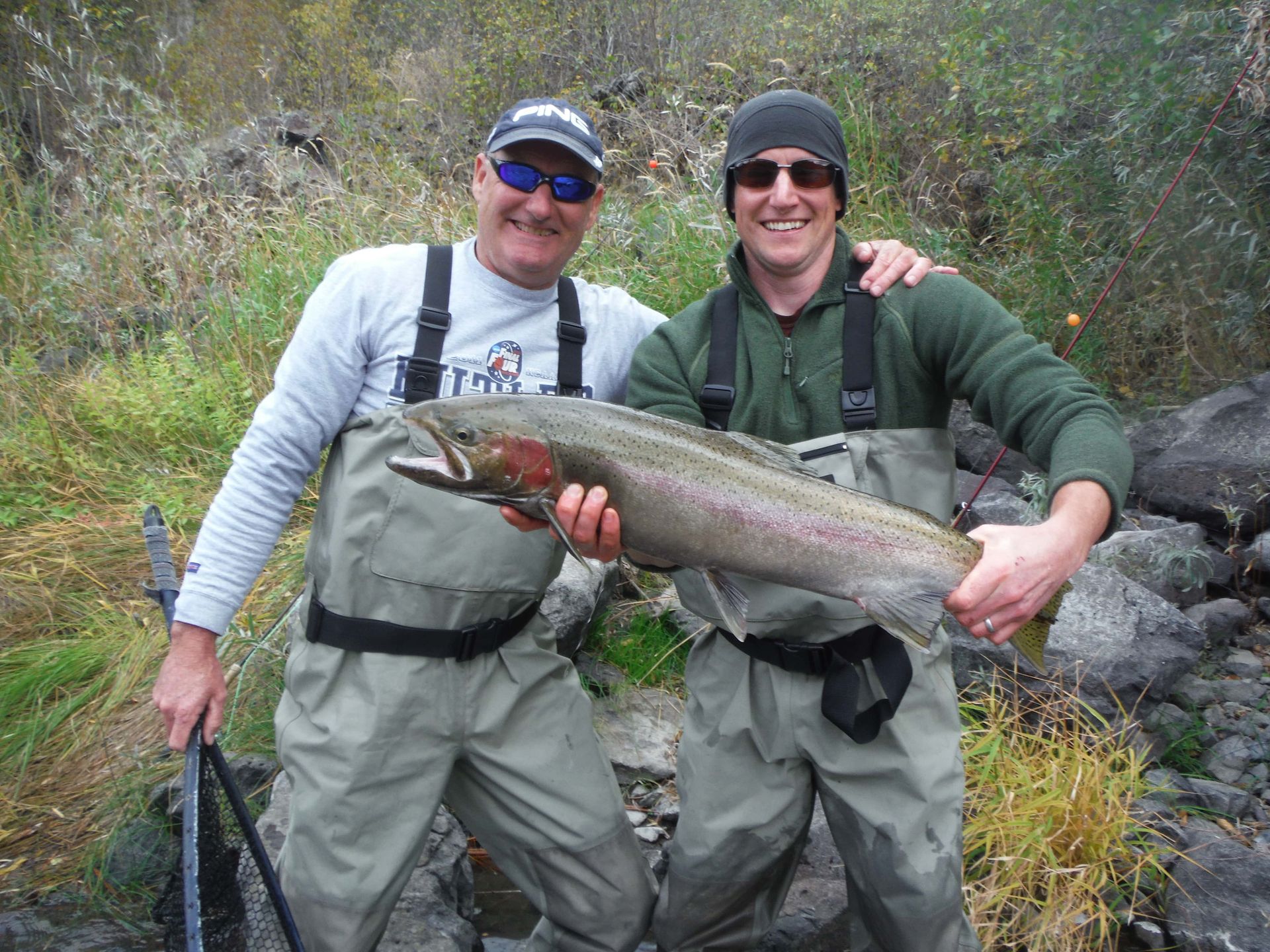 Two men standing next to each other holding a large fish