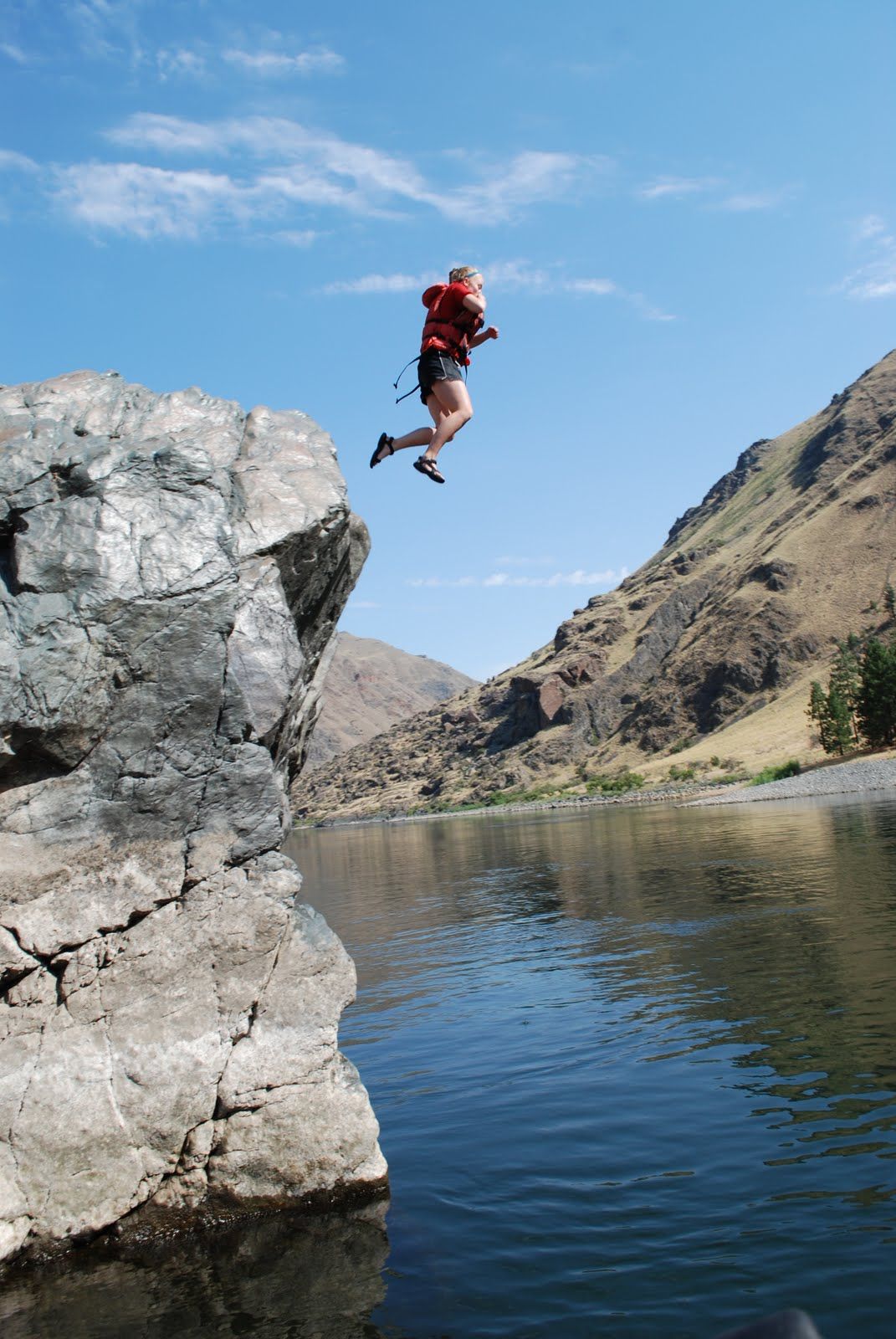 A person is jumping off a rock into a lake.