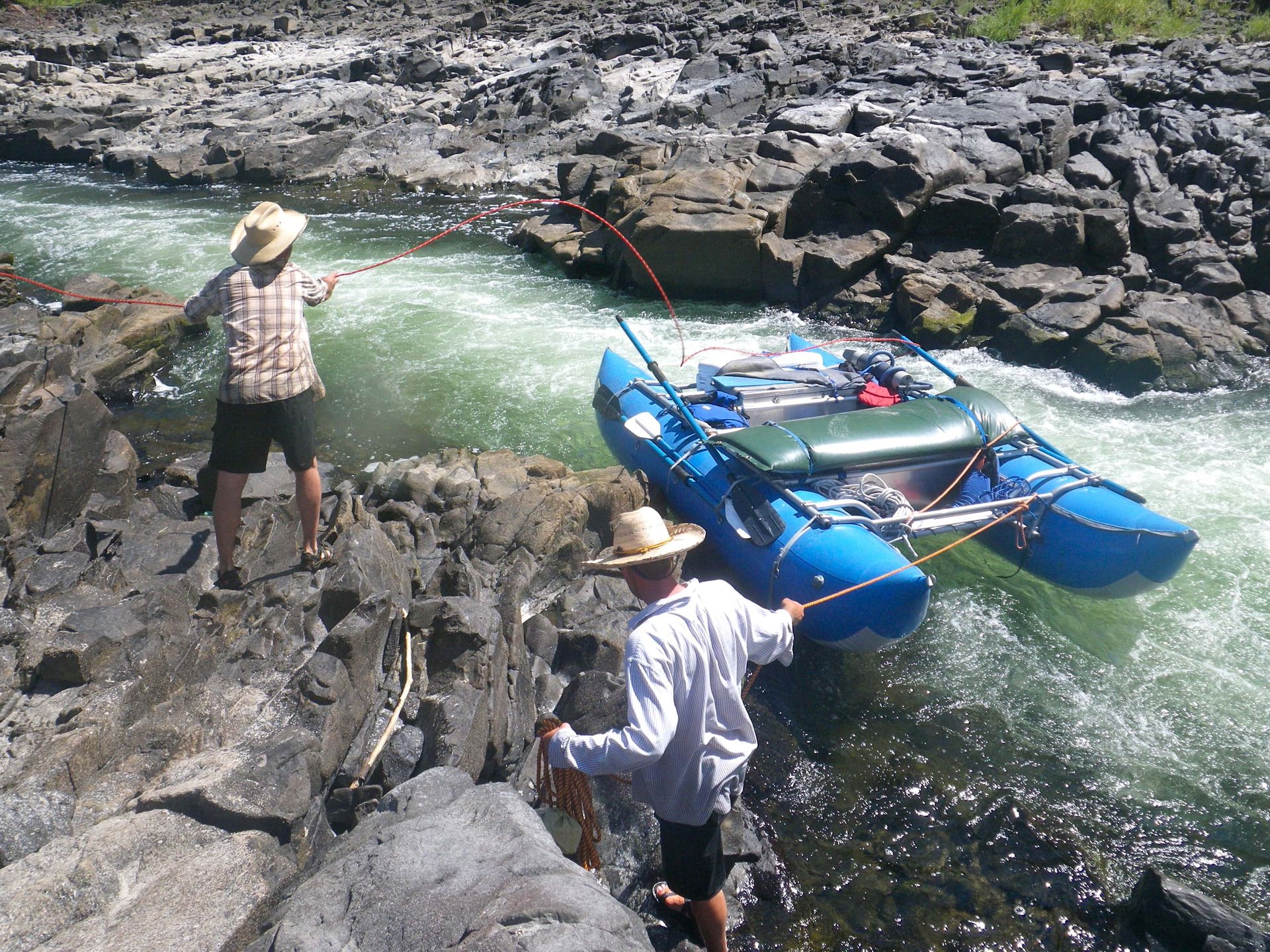 Two men are fishing in a river near a boat