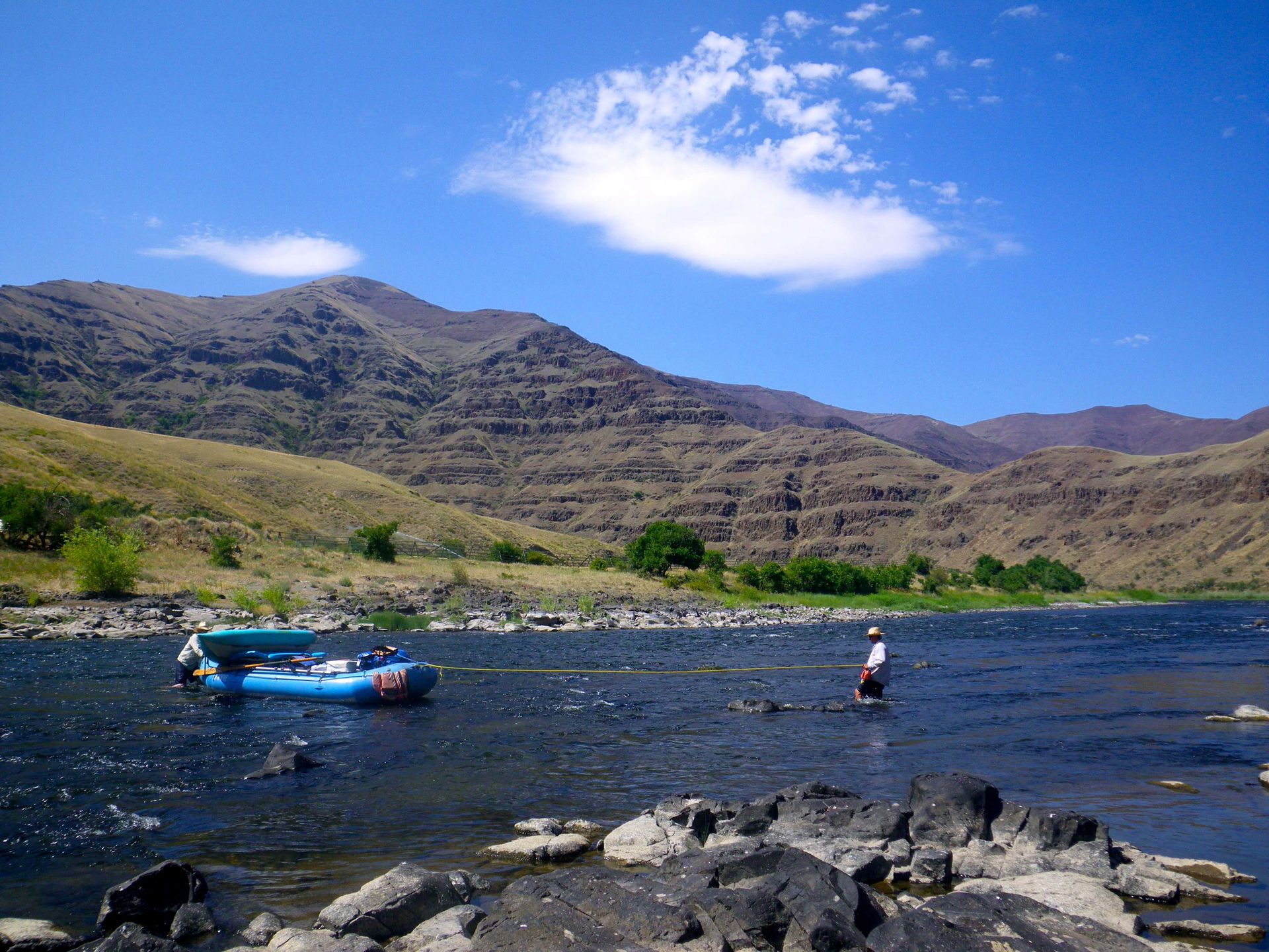 A river with mountains in the background and a boat in the water