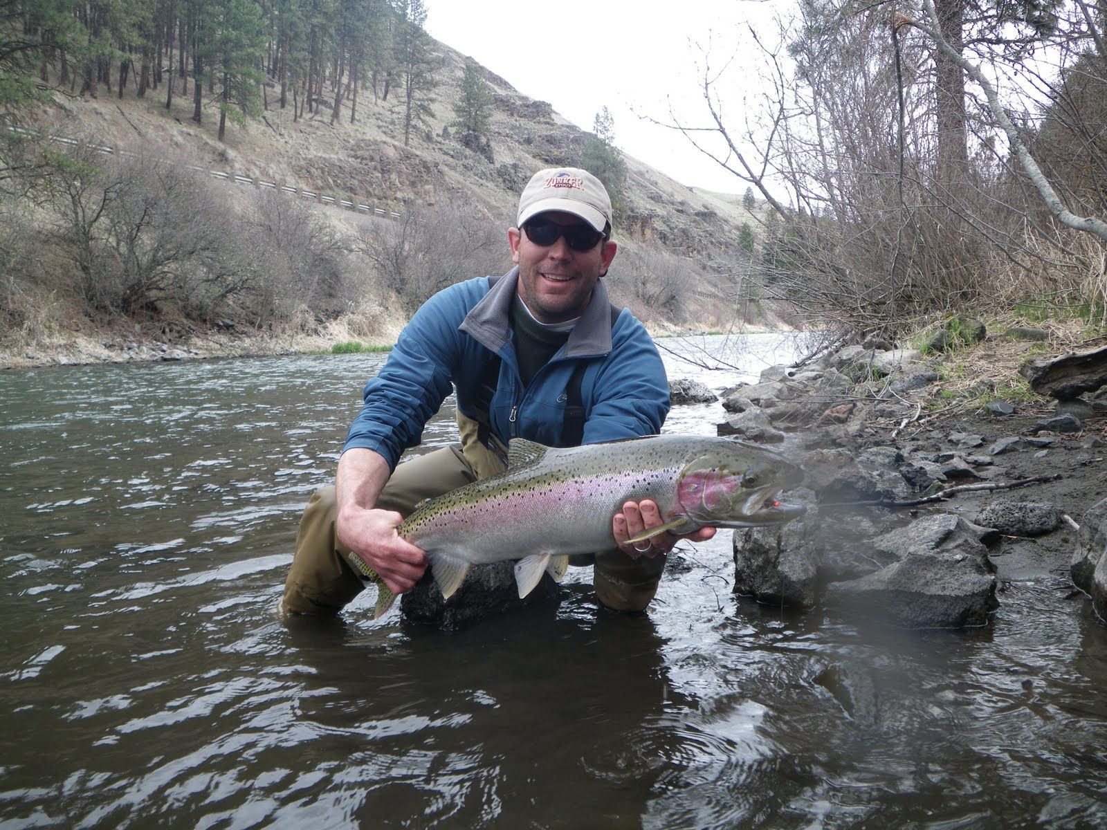 A man is kneeling in the water holding a large fish