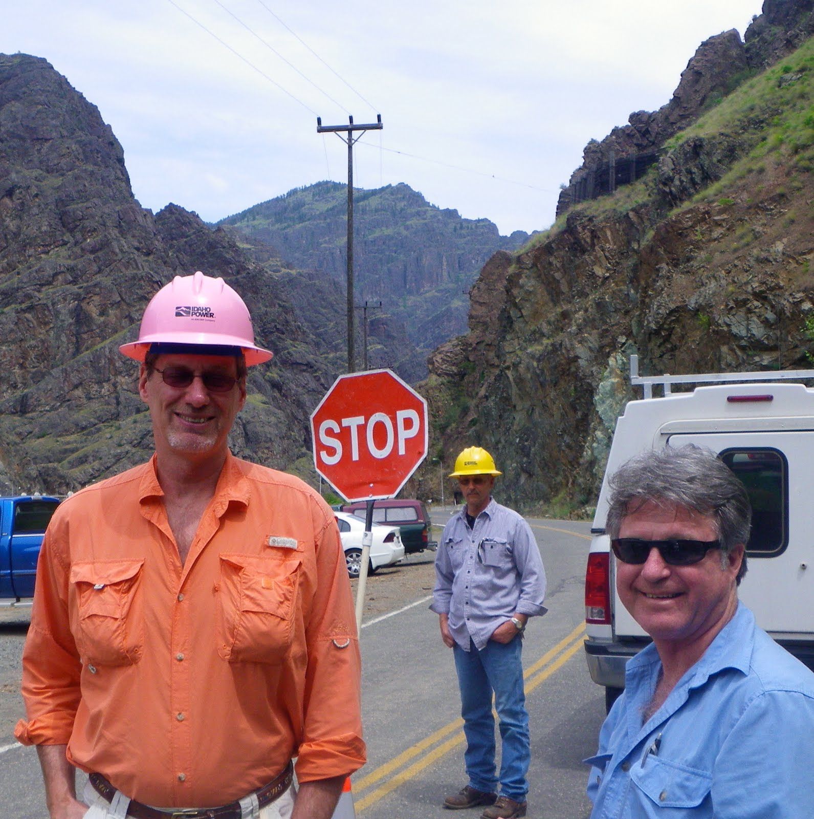 Three men are standing in front of a stop sign