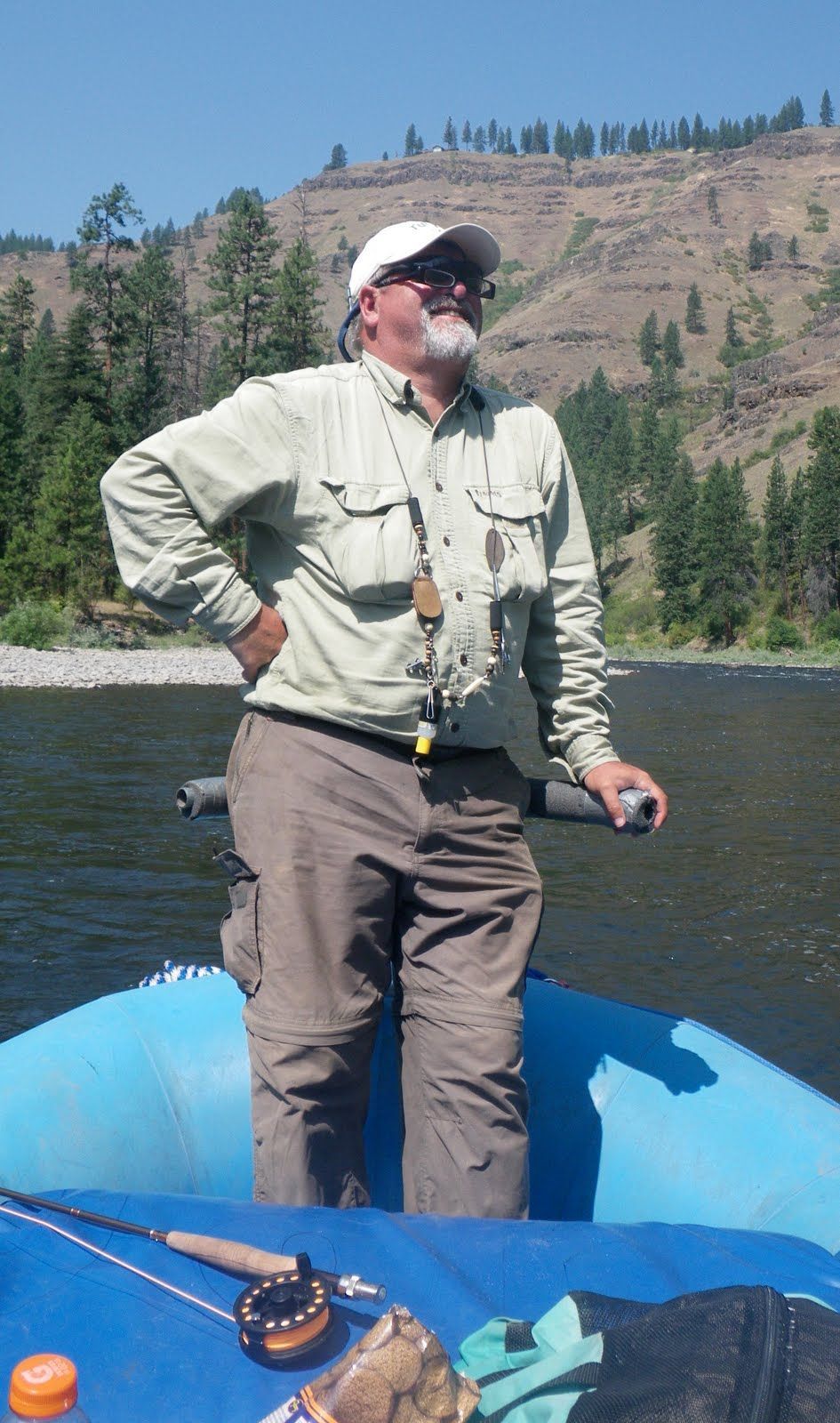 A man is standing in a raft on a river.