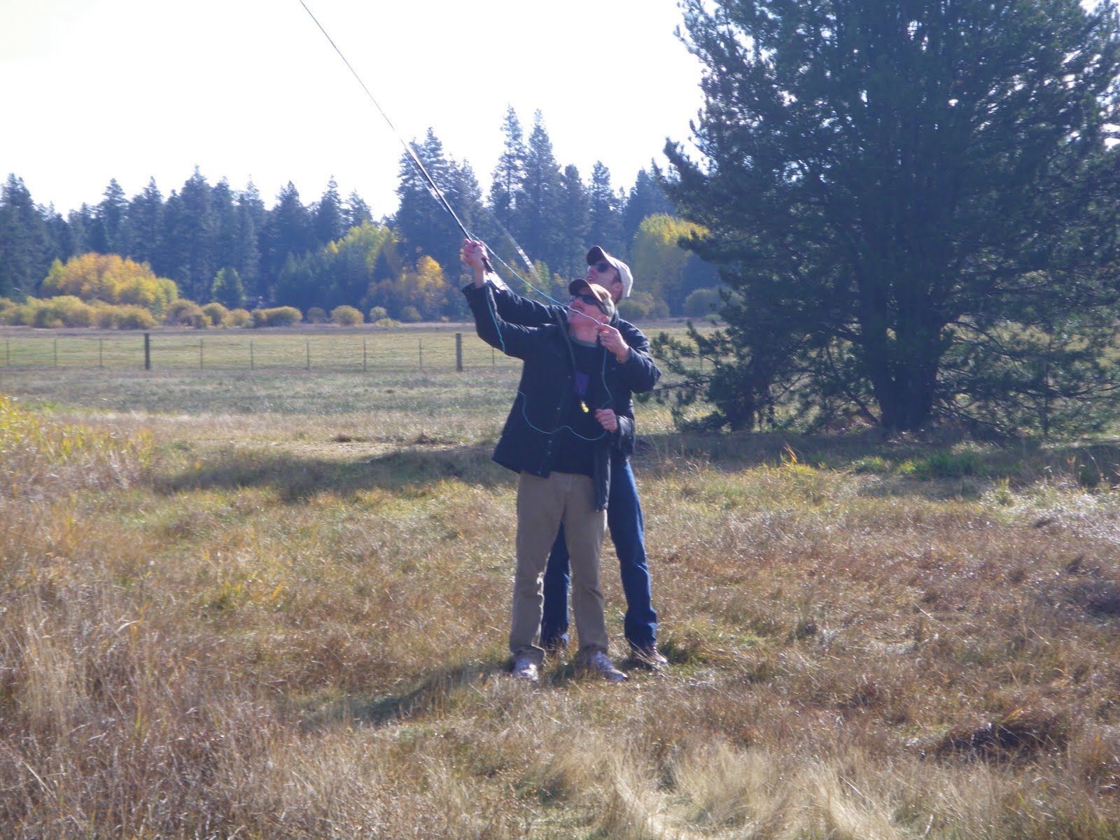 Two people standing in a field with trees in the background