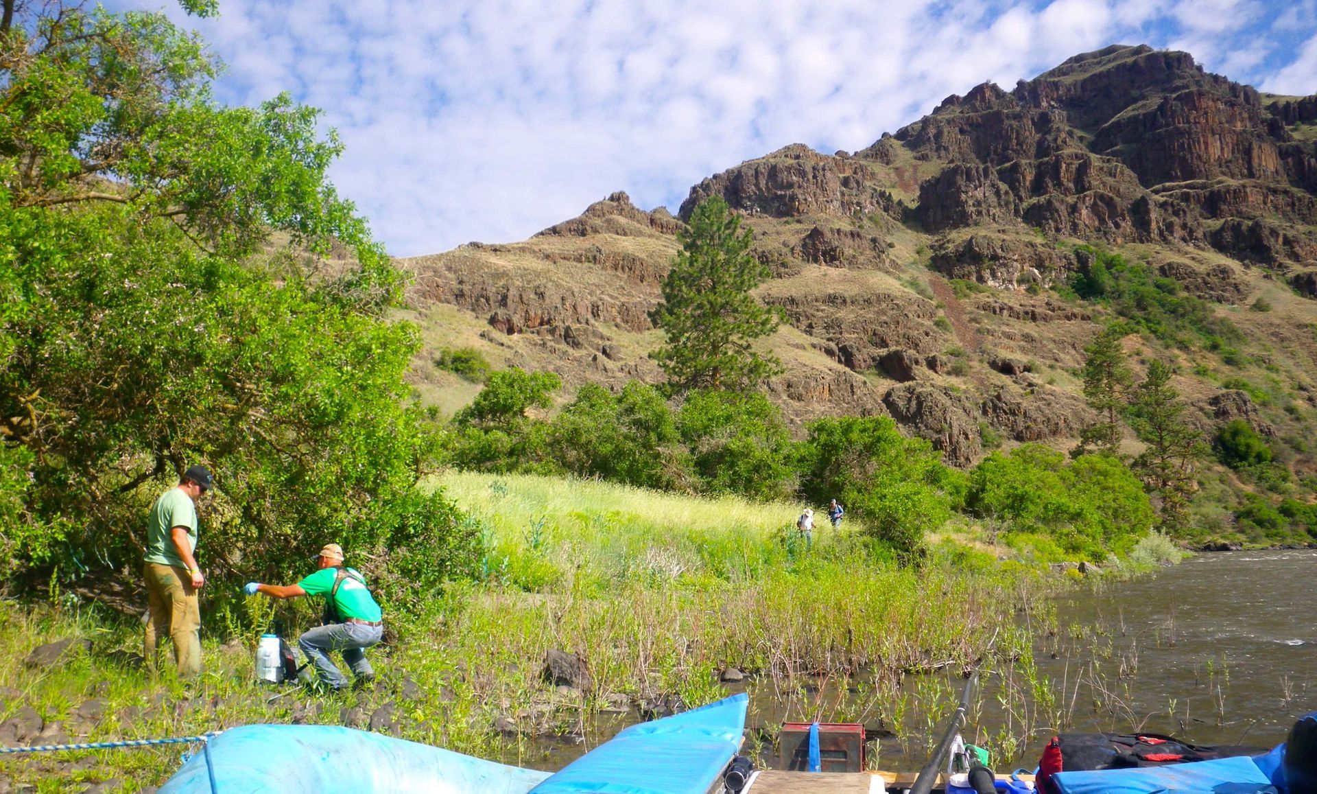 Group of People Sitting on The Shore of A Lake with A Mountain in The Background