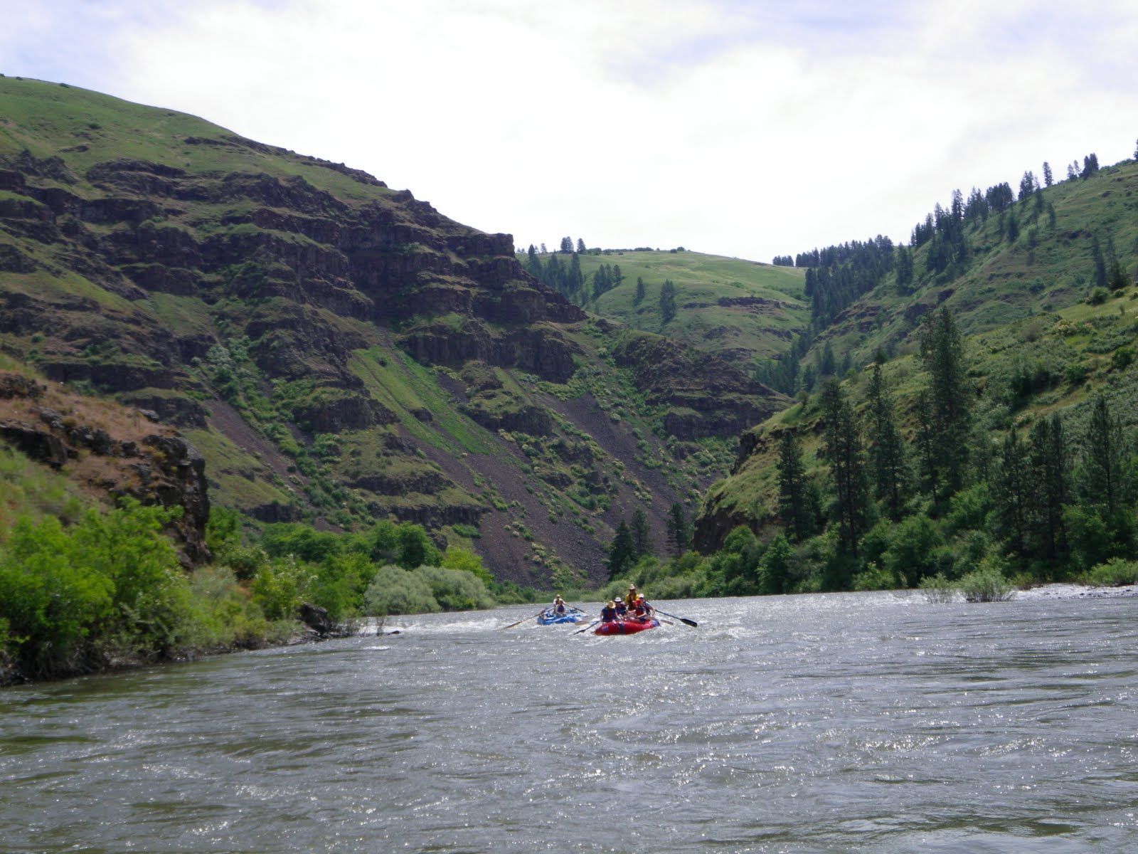 A group of people are rafting down a river with mountains in the background