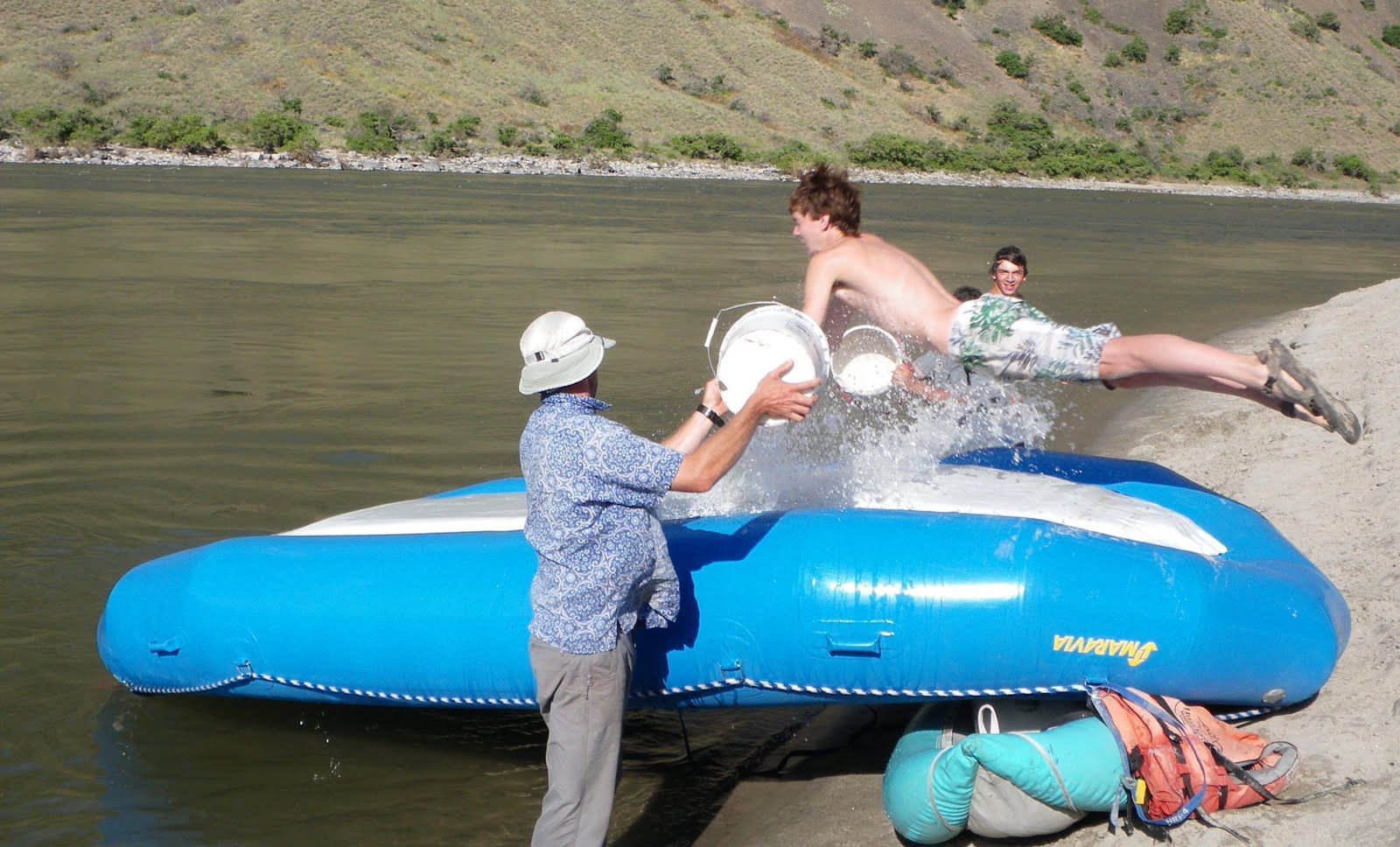 A man is pouring water from a bucket on a raft