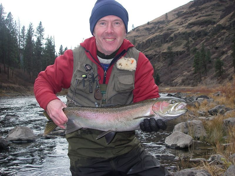 A man holding a large fish in front of a river