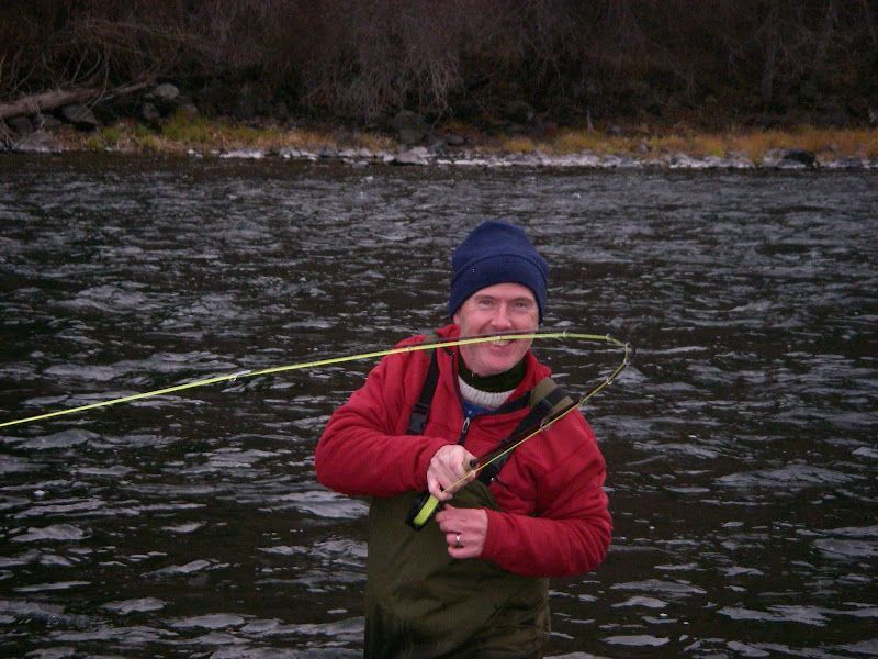 A man holding a large fish in front of a river