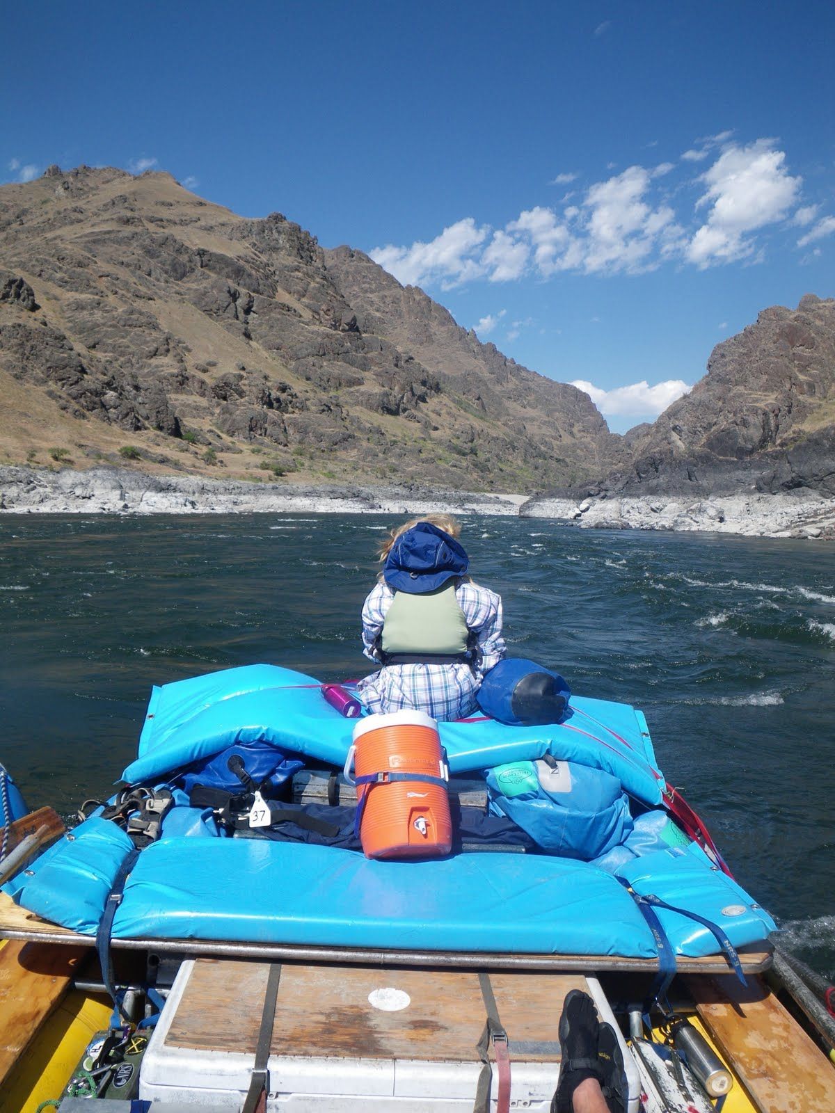 A person is sitting on the back of a boat on a river.