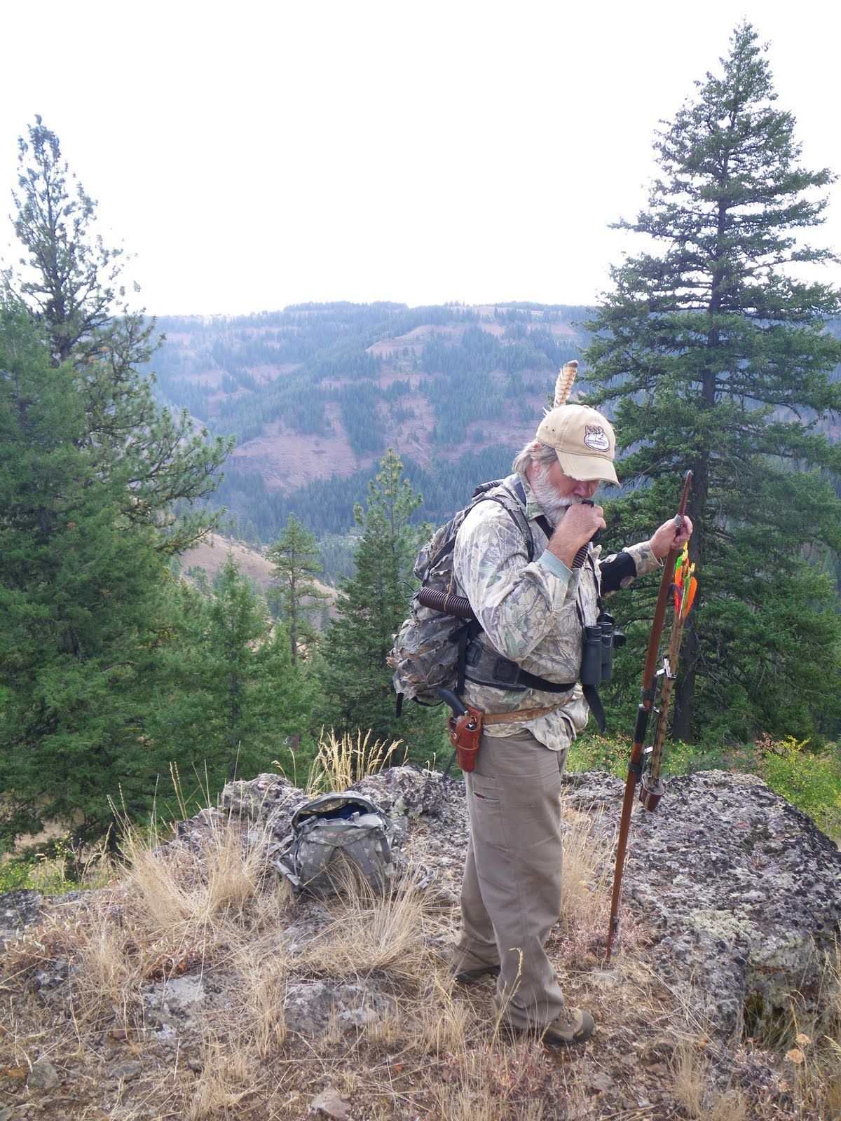 A man is standing on top of a hill talking on a cell phone.