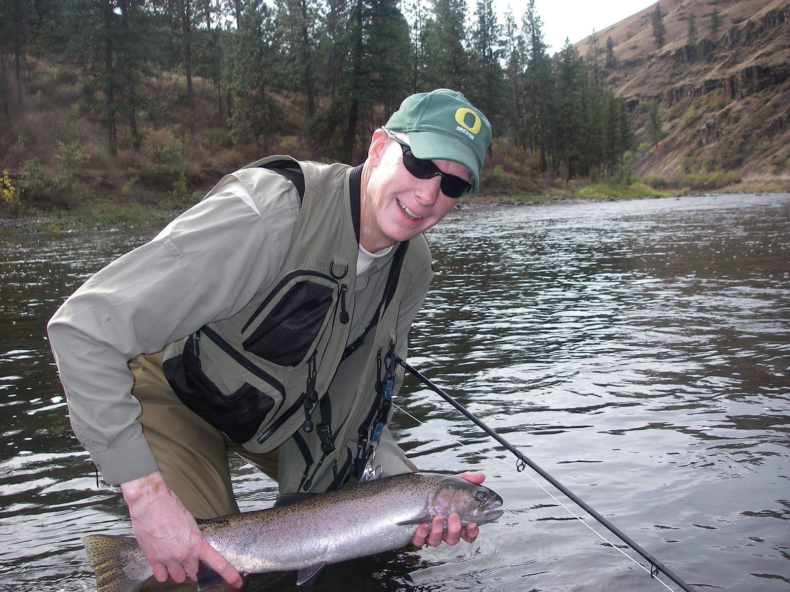 A man in a green hat is holding a large fish