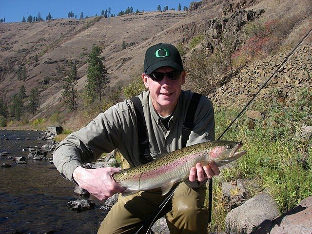 A man is holding a rainbow trout in his hands