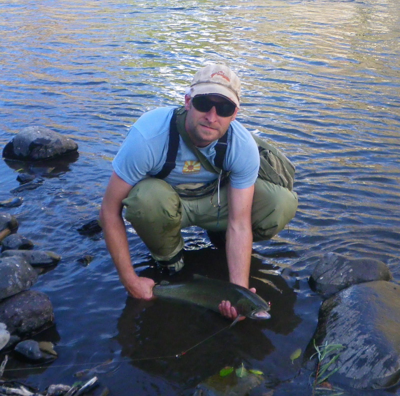 A man is kneeling in the water holding a fish