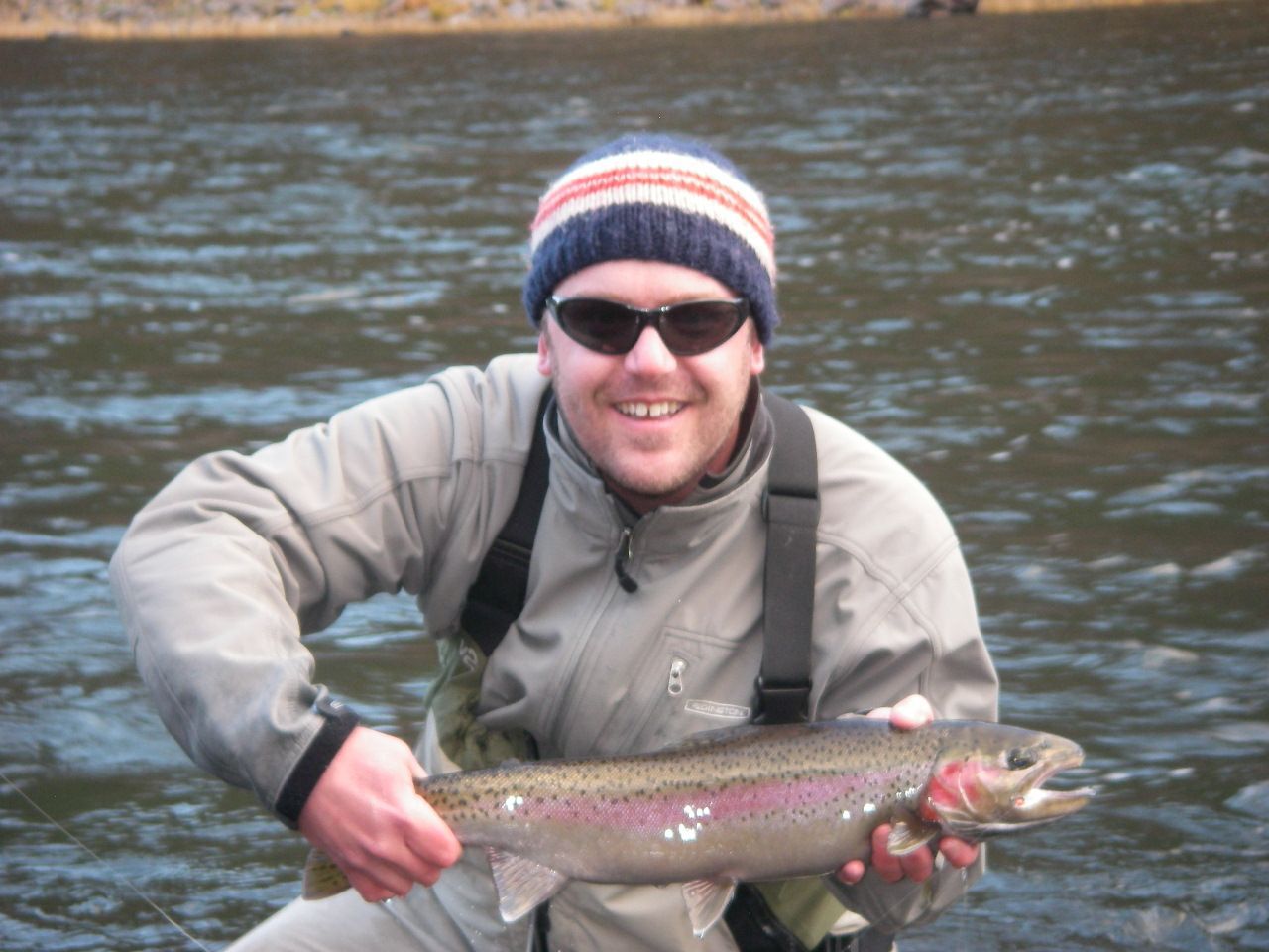 A man is holding a rainbow trout in his hands