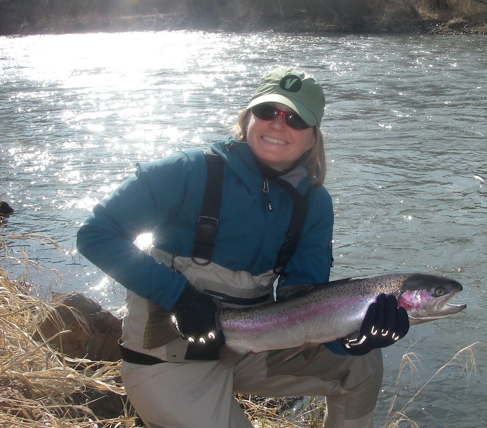 A woman in a green hat is holding a large fish