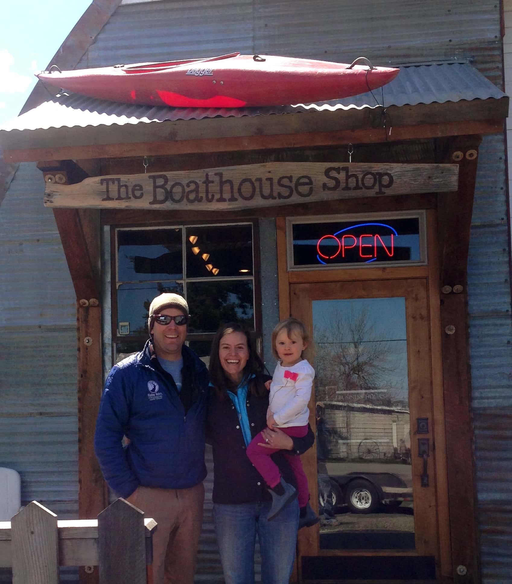 A man and woman standing in front of the boathouse shop