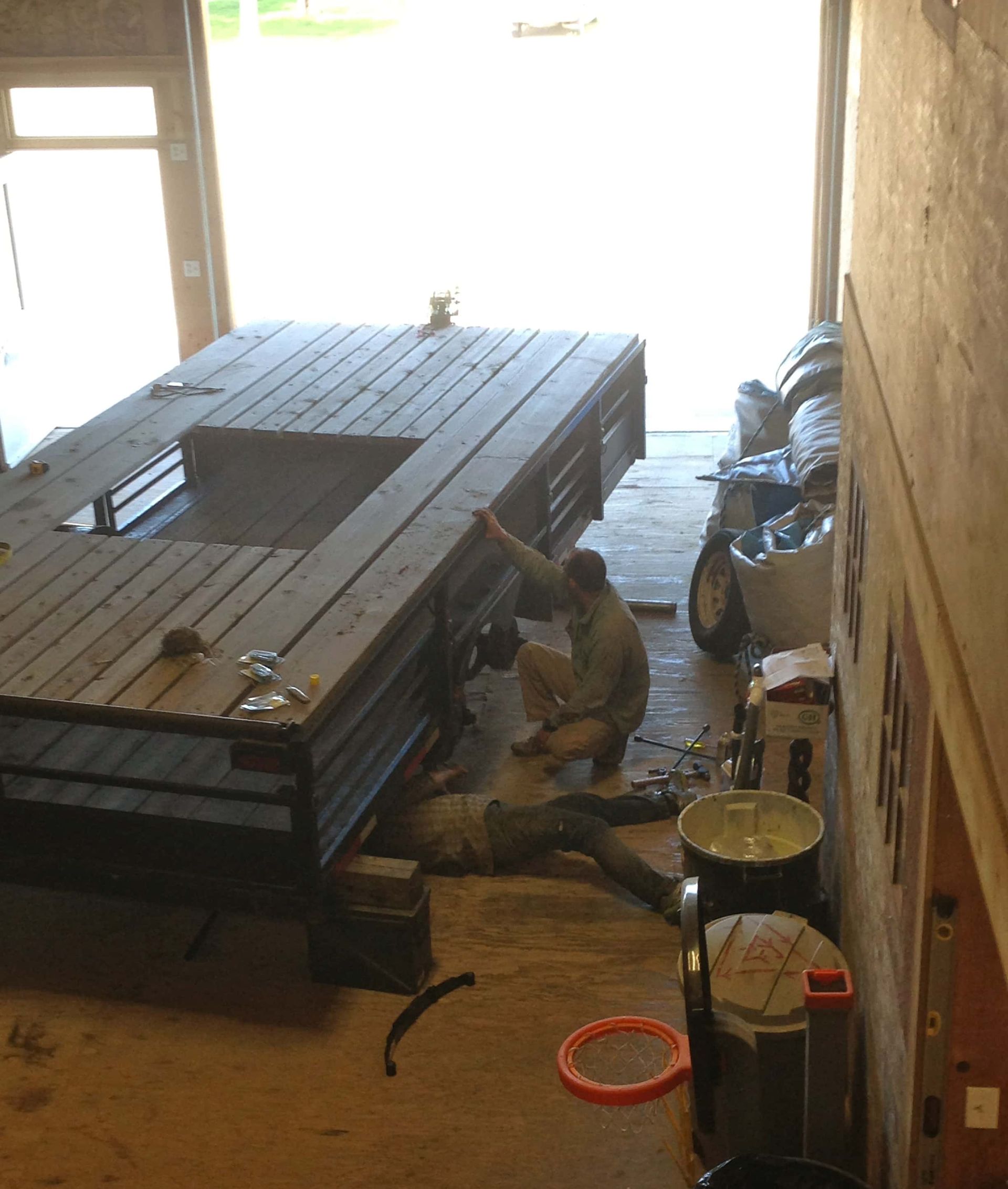 A man is working on a wooden table in a garage