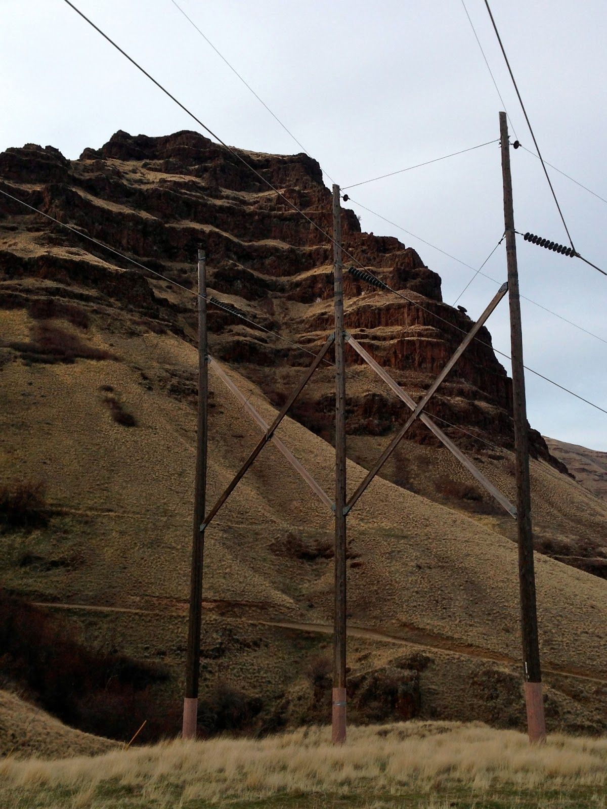 A row of power lines in front of a mountain
