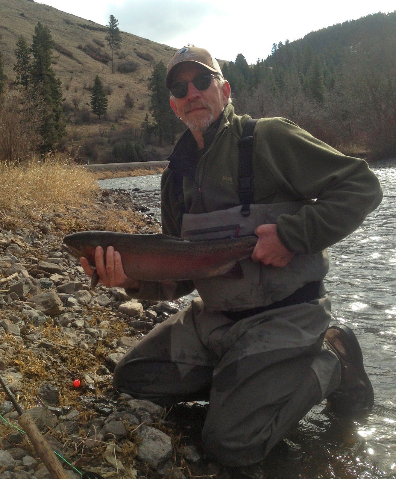 A man is kneeling down holding a large fish