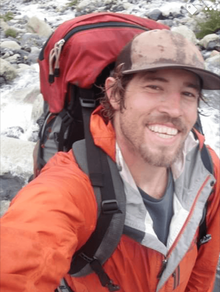 A man with a backpack is smiling for the camera
