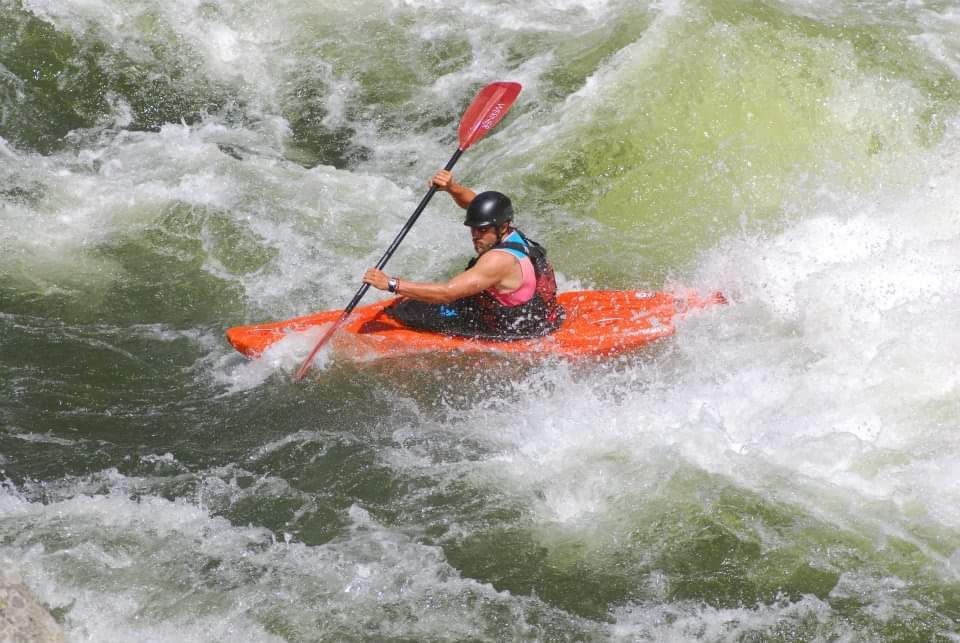 A person is paddling a kayak down a river.