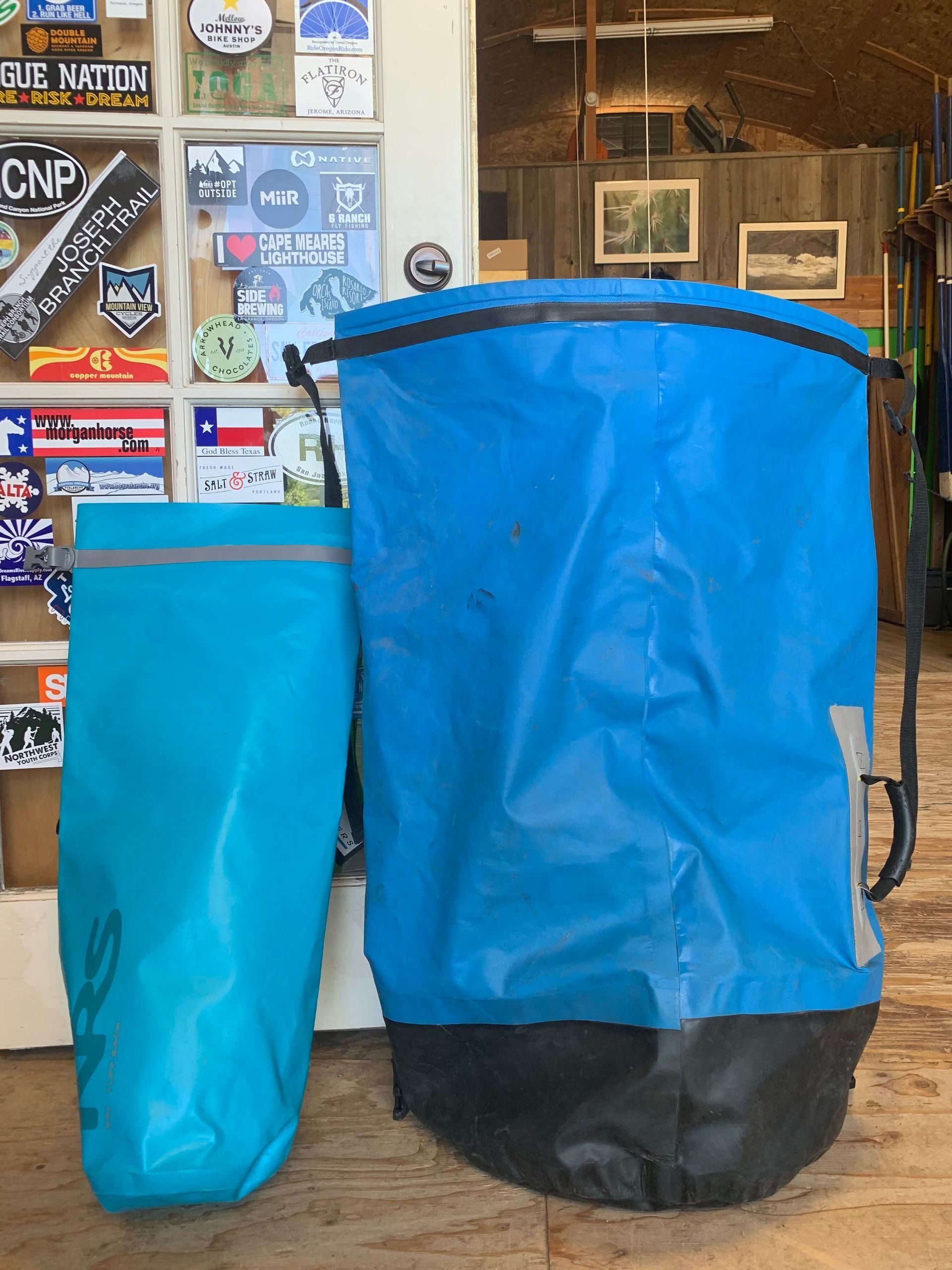 Two blue bags are sitting next to each other on a wooden floor