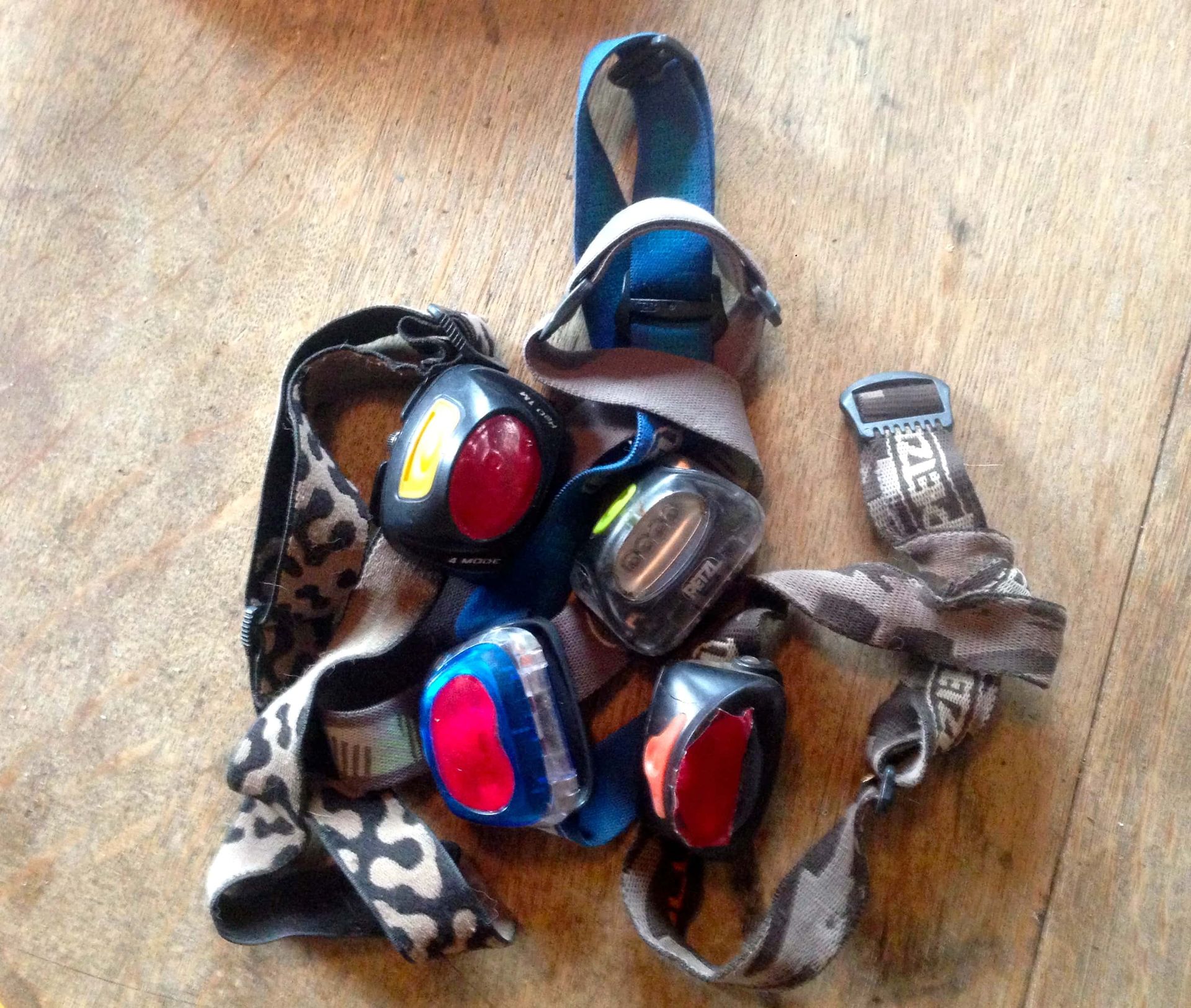 A bunch of headlamps are sitting on a wooden table.