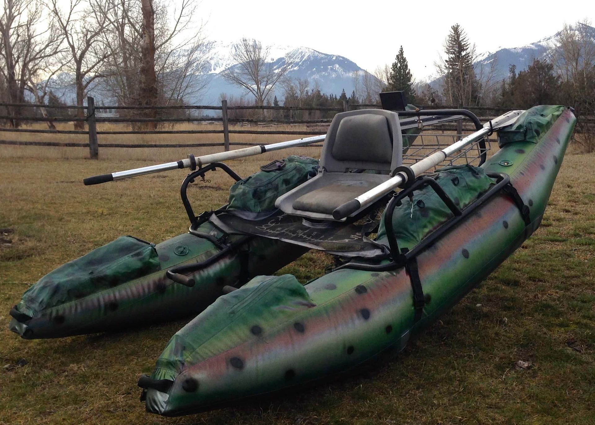 An inflatable boat with a seat and oars is sitting in the grass