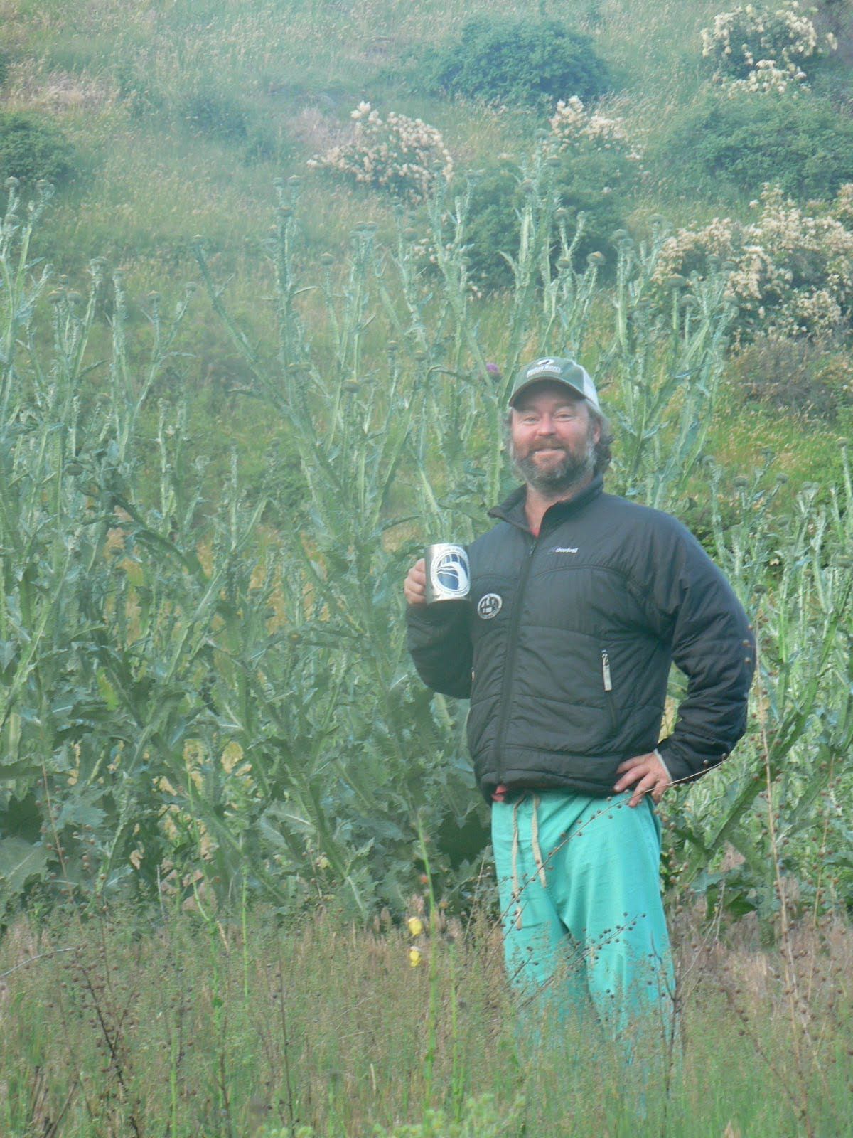 A man standing in a field holding a cup with the number 6 on it