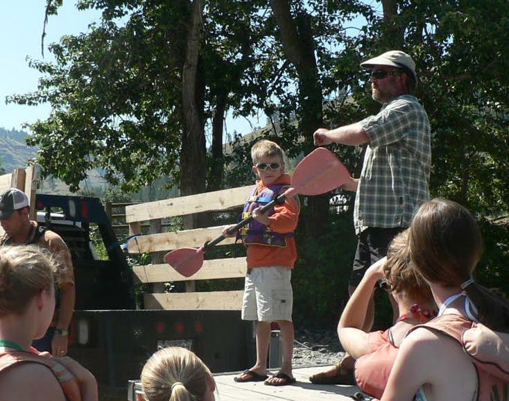 A man teaching a boy how to paddle a boat