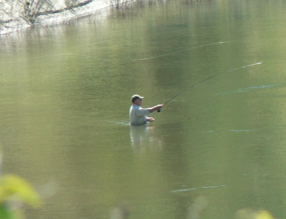 A man is fishing in a lake with a fishing rod.